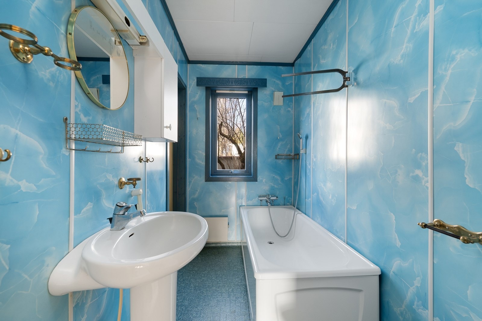 Badet i første etasje har eldre standard med våtromsbelegg på gulv, våtromsplater på veggene og badekar. Galleribilde