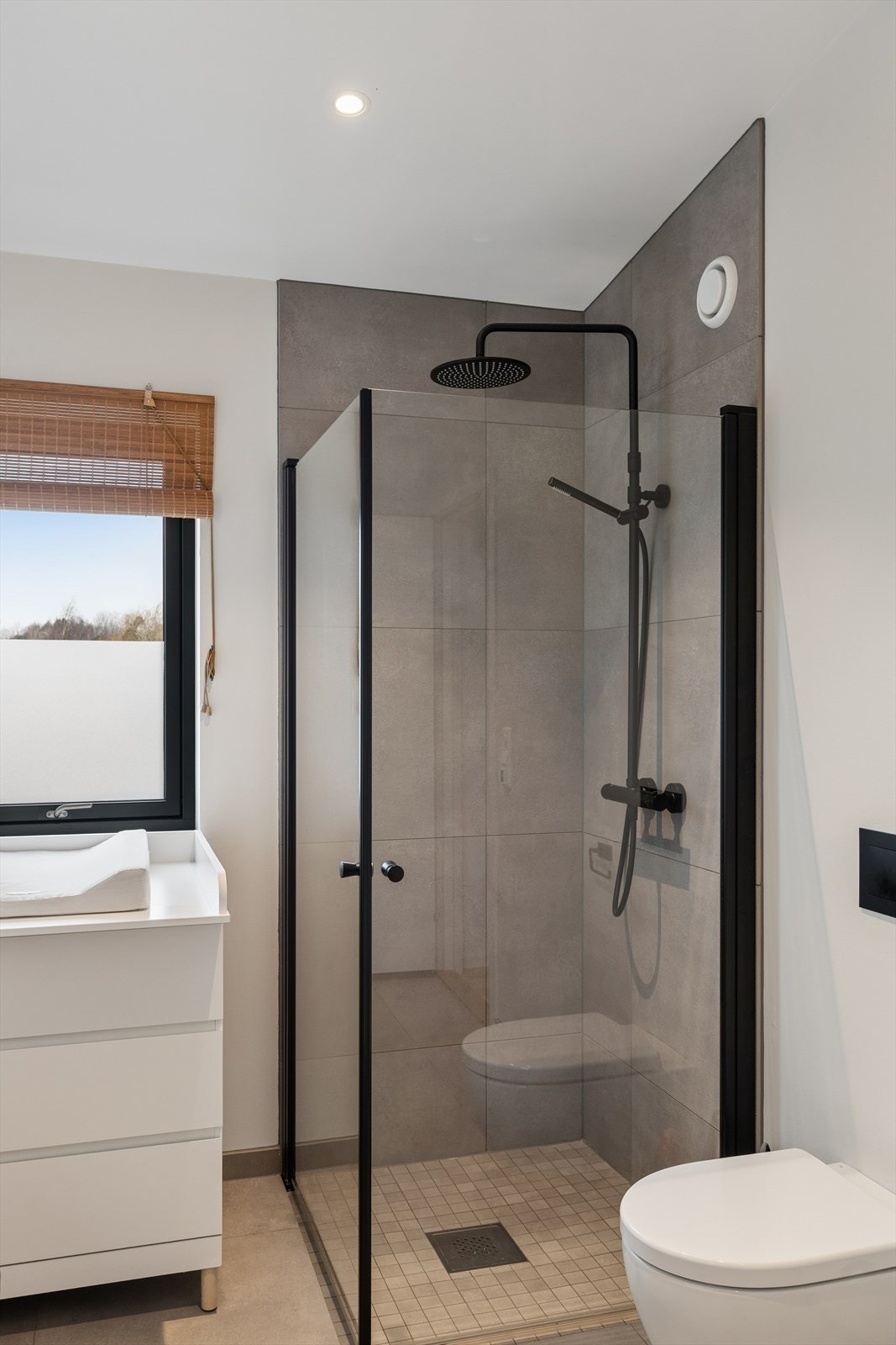 Dusjhjørne med glassdører og flislagte vegger. Vindu på badet gir naturlig lysinnslipp. Galleribilde