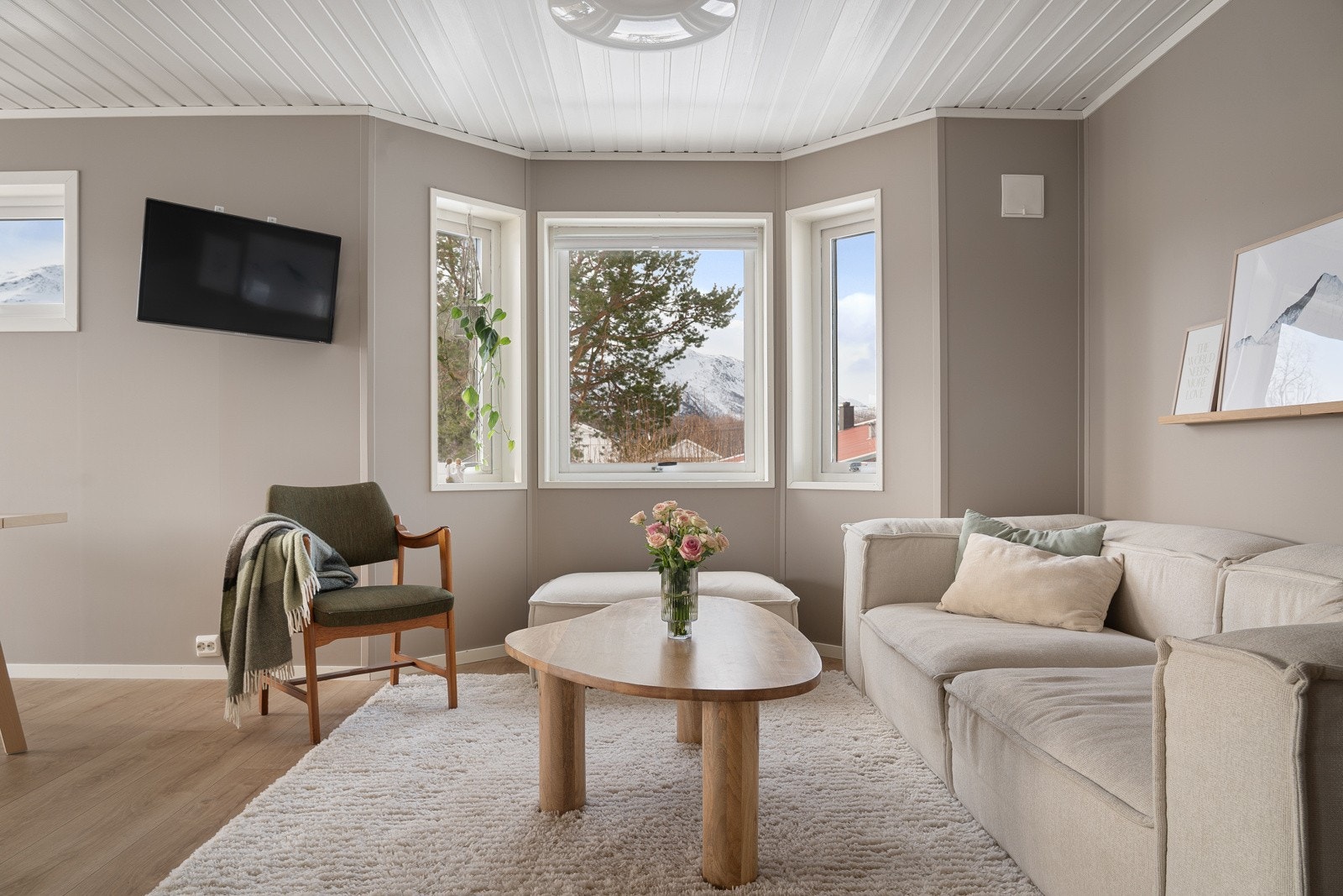 Stuen fremstår både lun og luftig, med store vindusflater som lar dagslyset strømme inn.