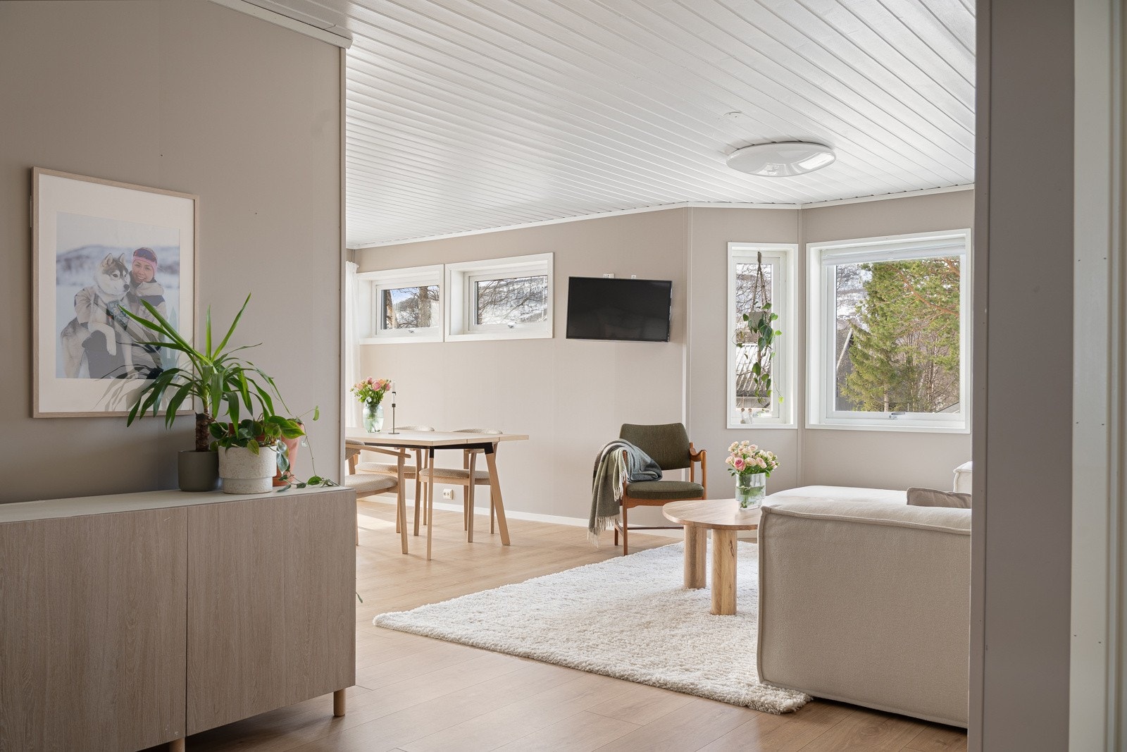 Stue med laminatgulv og store vindusflater som gir rikelig med lys inn