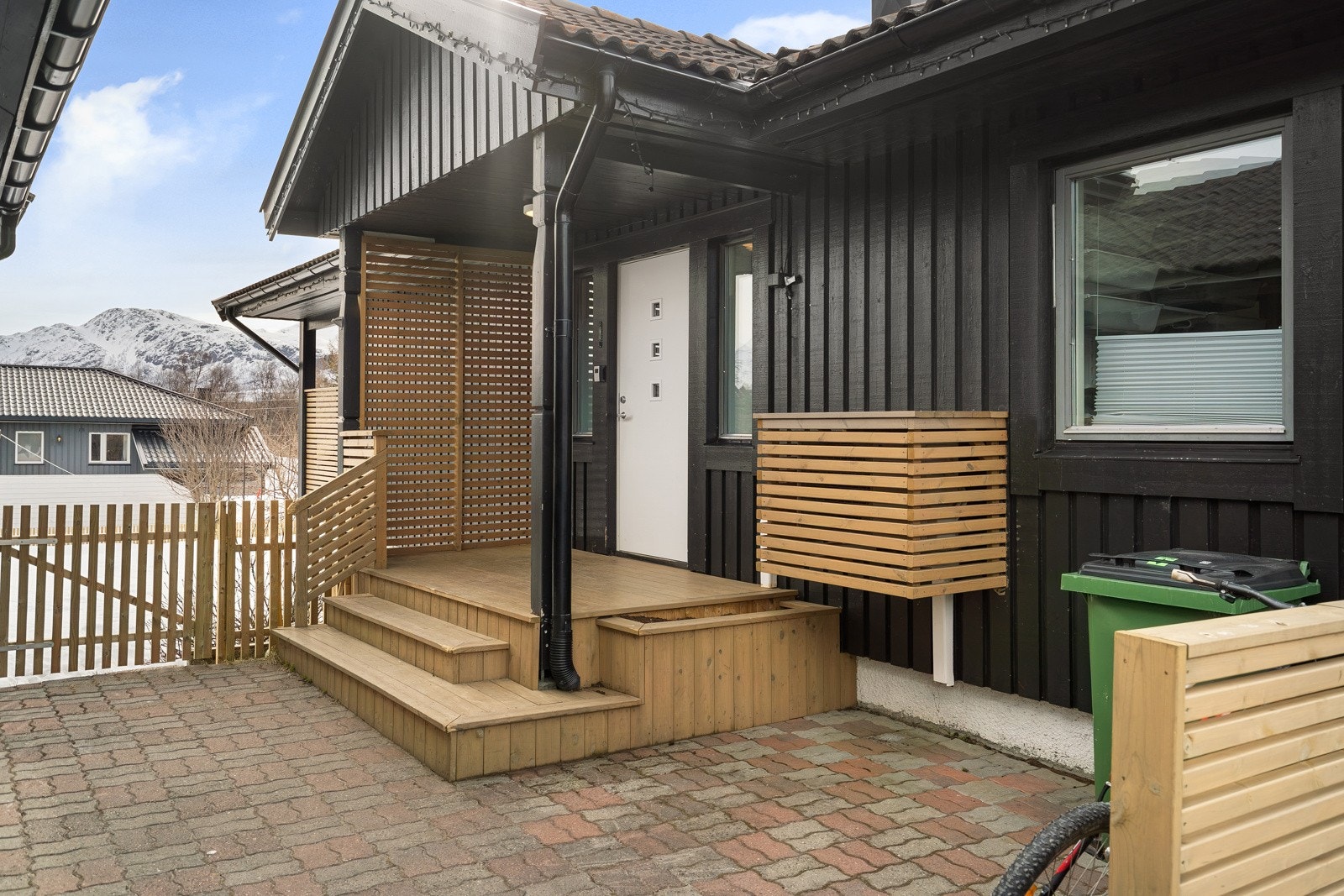 Takoverbygd inngangsparti med repos. Tomten er brosteinbelagt ved inngangspartiet.