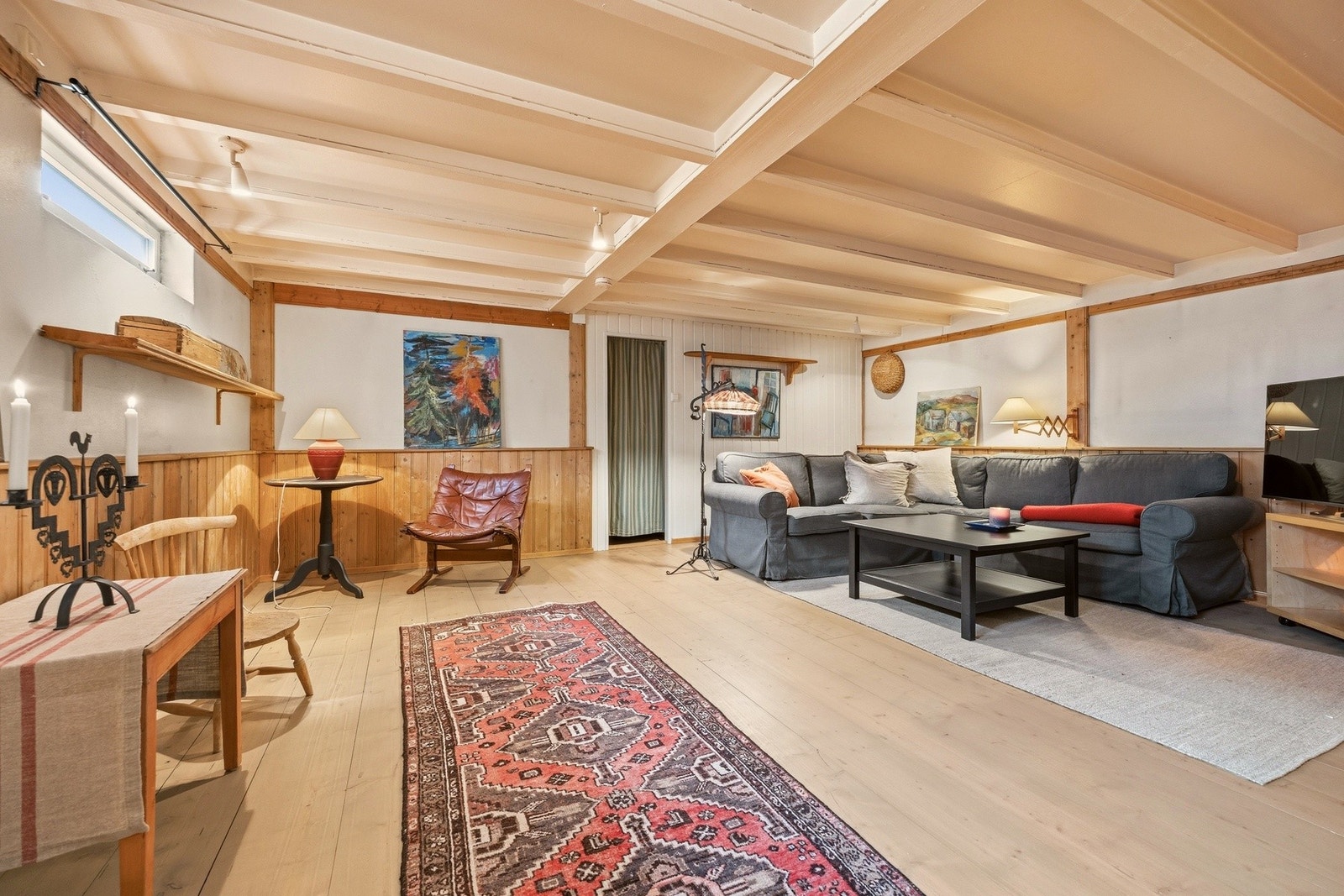 Stor kjellerstue med god plass til sofa og TV med tilhørende møblement Galleribilde