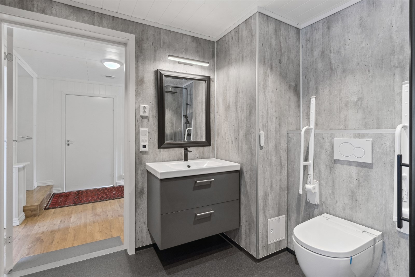 Badet har servant i innredning, vegghengt toalett og dusjhjørne. Det er opplegg for vaskemaskin Galleribilde