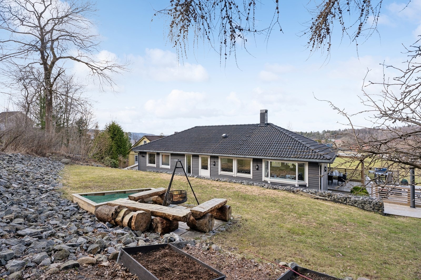Den store, skrånende tomten er pent opparbeidet med plen, beplantning og støttemurer. Galleribilde