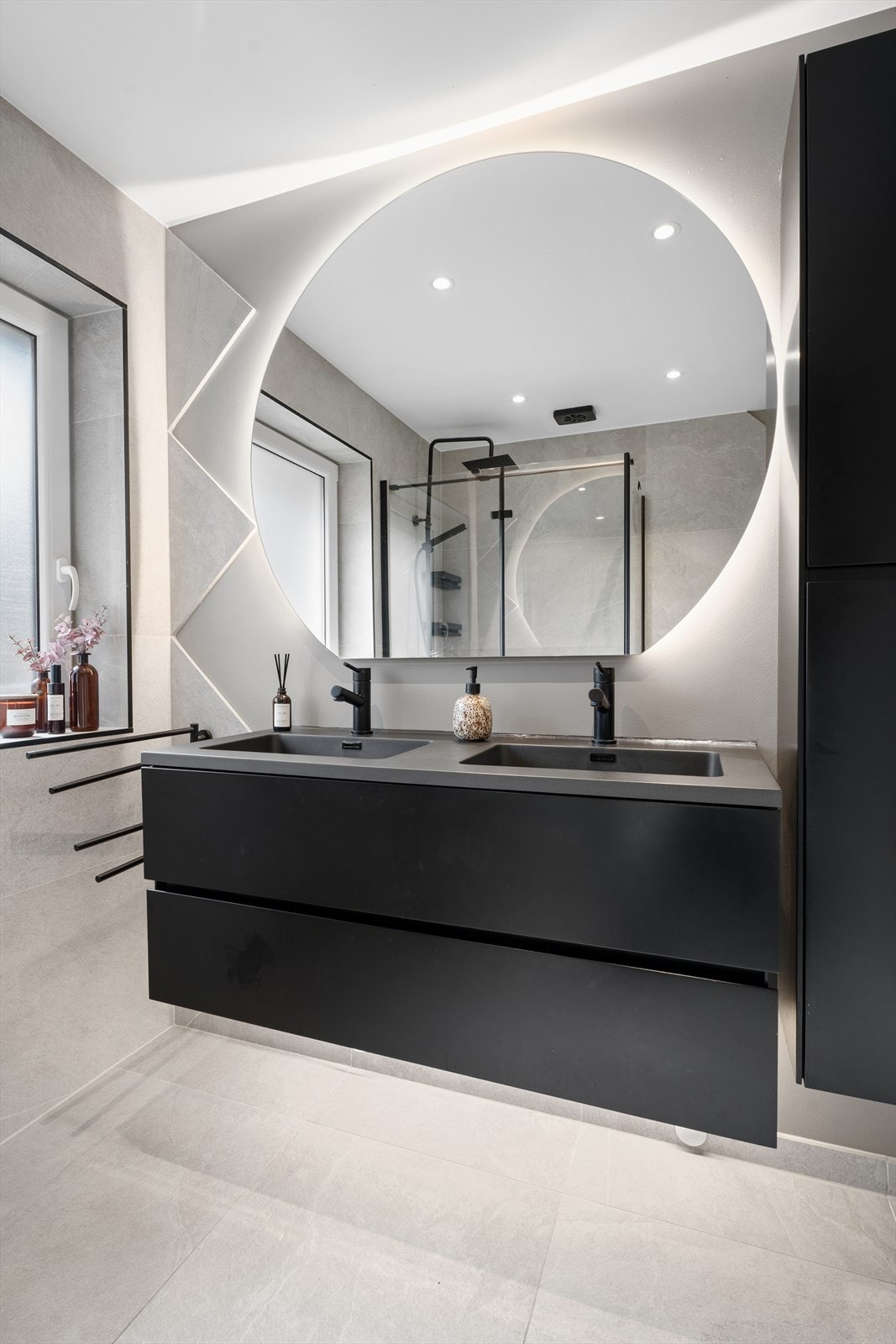 Innredningen på hovedbadet inkluderer doble servanter i et moderne møbel, høyskap og et stort, bakbelyst speil. Galleribilde