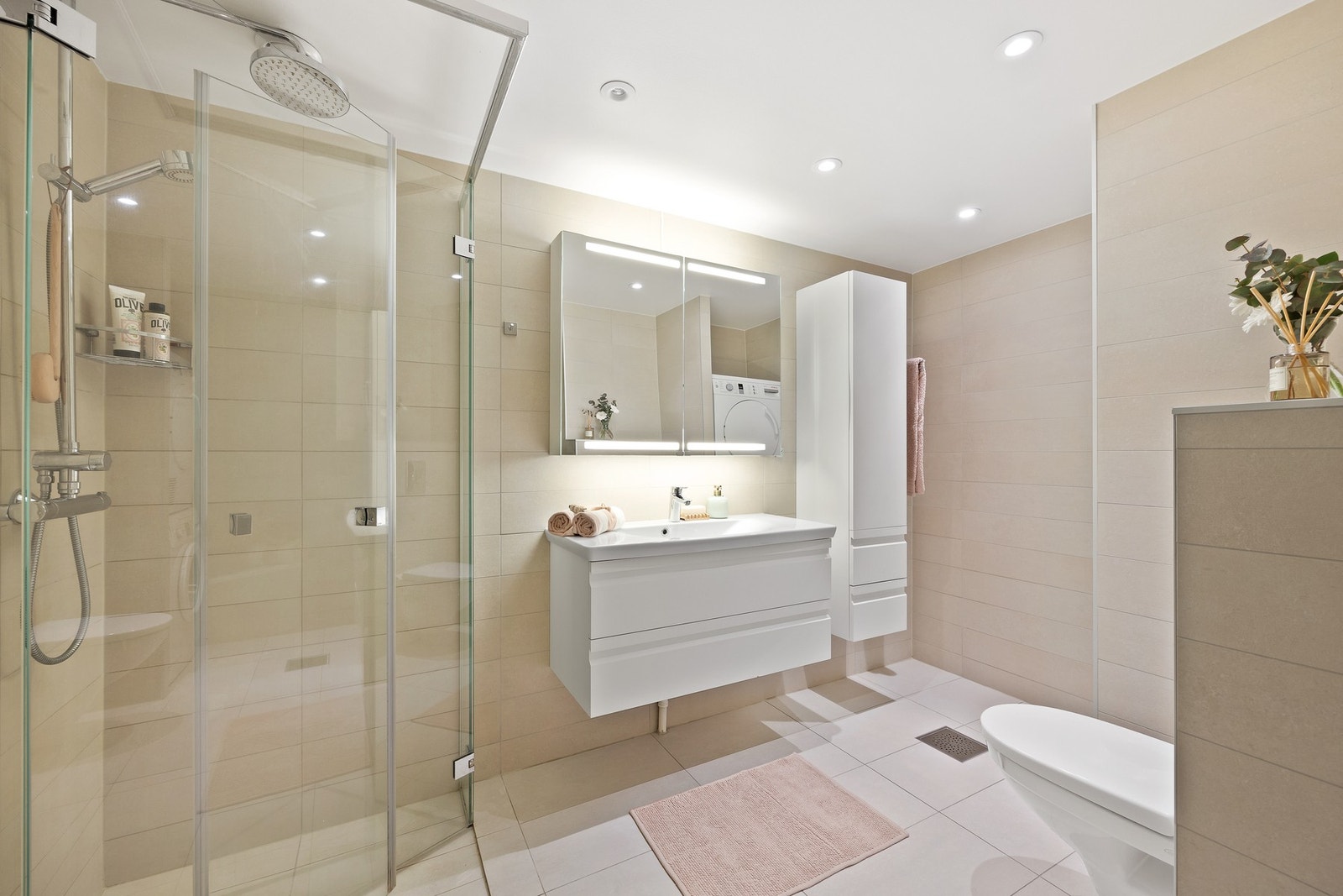 Badet er innredet med dusj med innfellbare dusjvegger, vegghengt servantskap med nedfelt servant, speilskap, skap og vegghengt toalett. Galleribilde