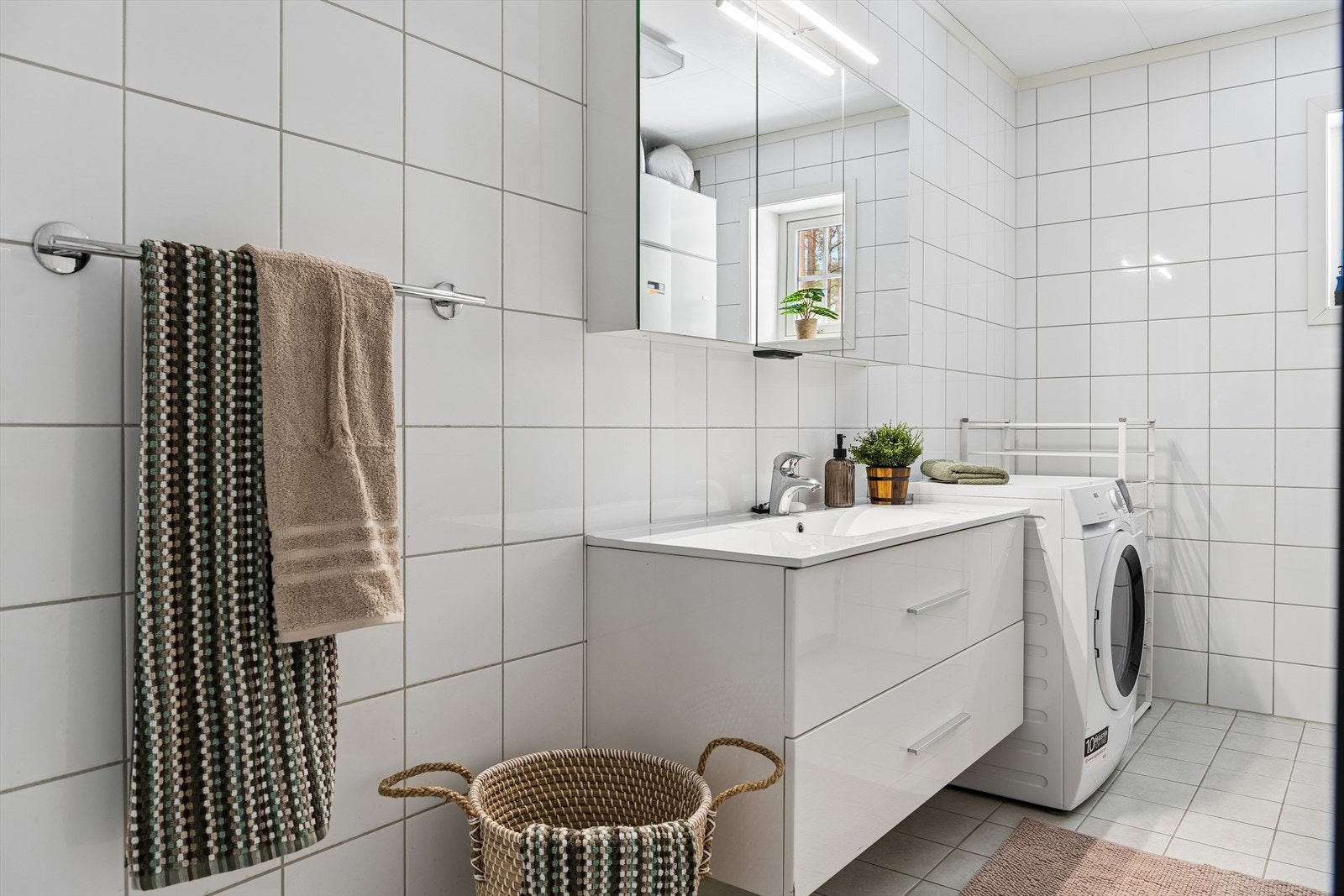 Det største av boligens to bad er kombinert med vaskerom. Flislagte overflater, vannbåren gulvvarme og opplegg for vaskemaskin. Galleribilde