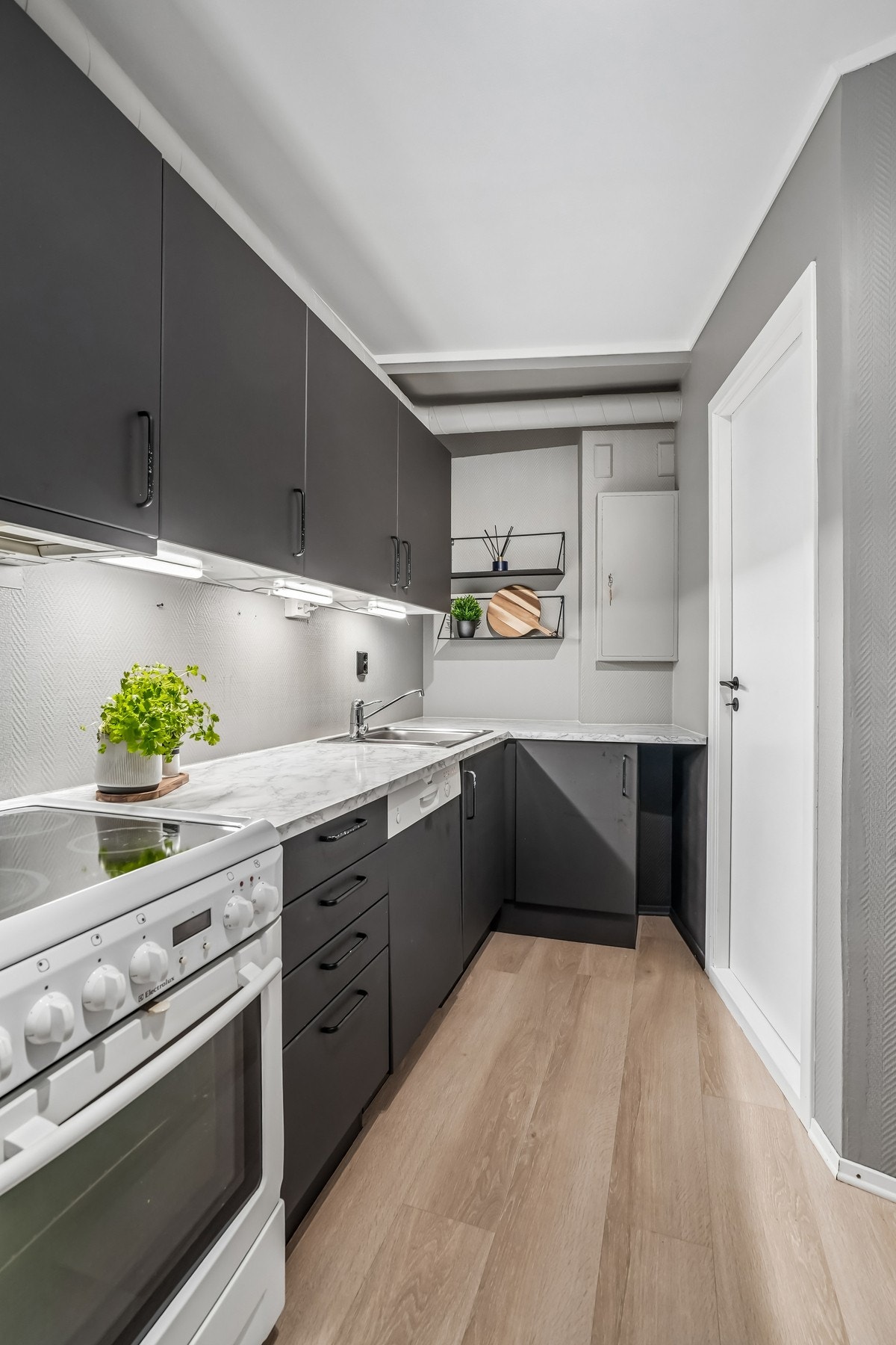 Kjøkkeninnredningen er av glatt utførelse med gråtonede fronter og en laminat benkeplate (denne er foliert). Galleribilde