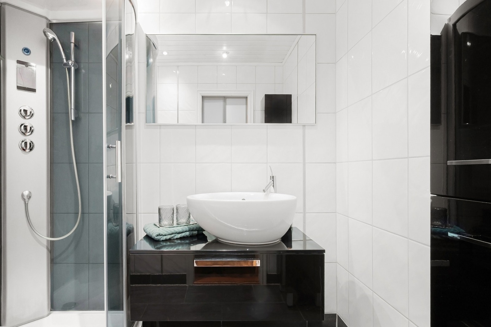 Badet er innredet med dusjkabinett, vegghengt toalett, servantseksjon med skuffer og speil. Galleribilde