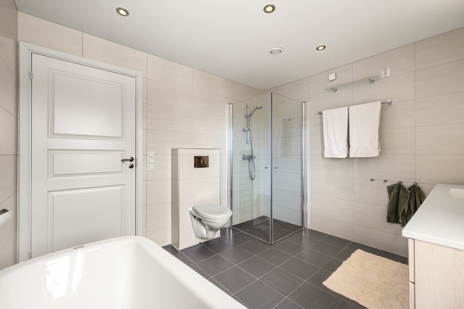 Badet har flislagte overflater med behagelig varme i gulvet og downlightsbelysning i taket. Galleribilde