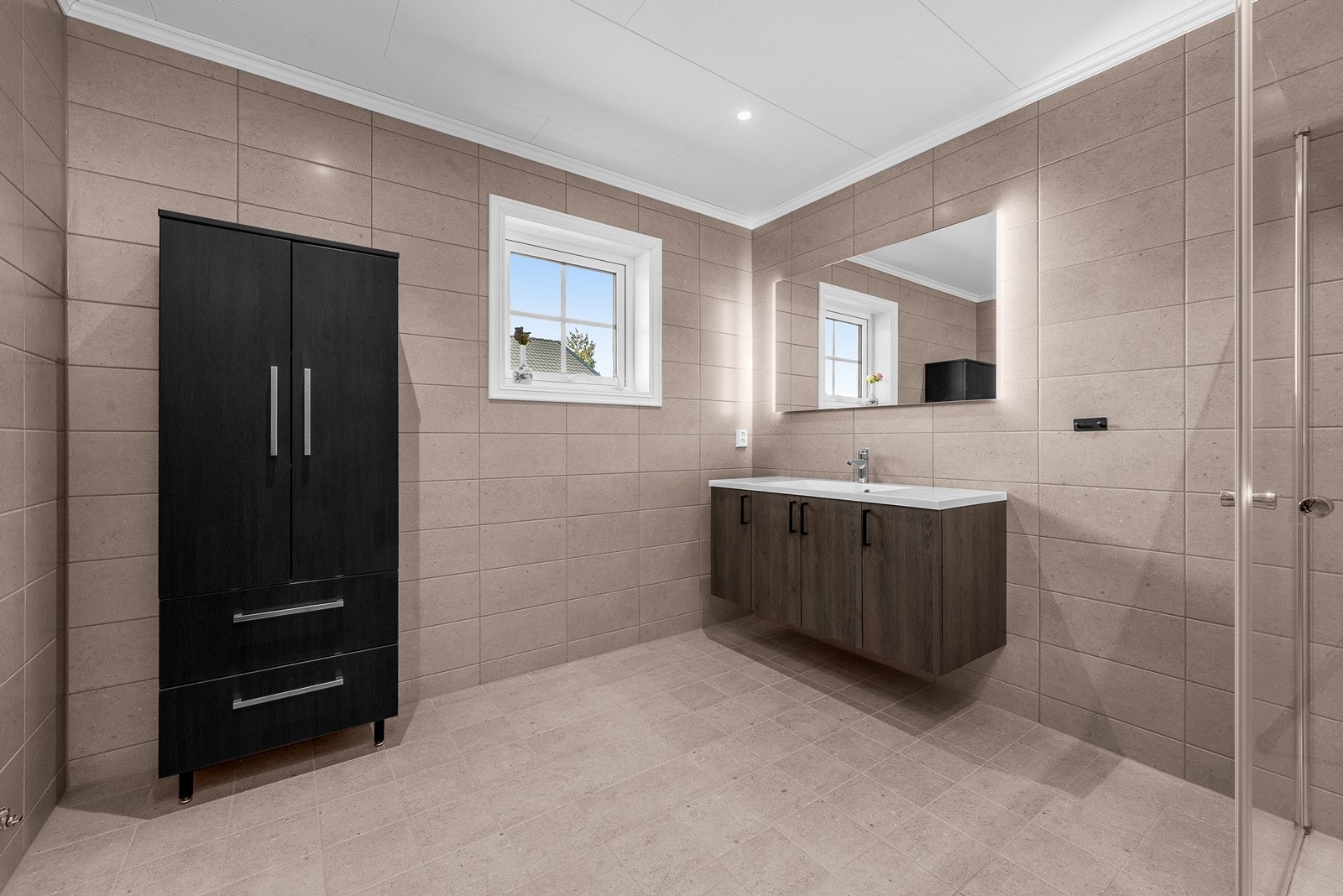 Badet er moderne og stilrent med store fliser i lun farge og moderne innredning. Galleribilde