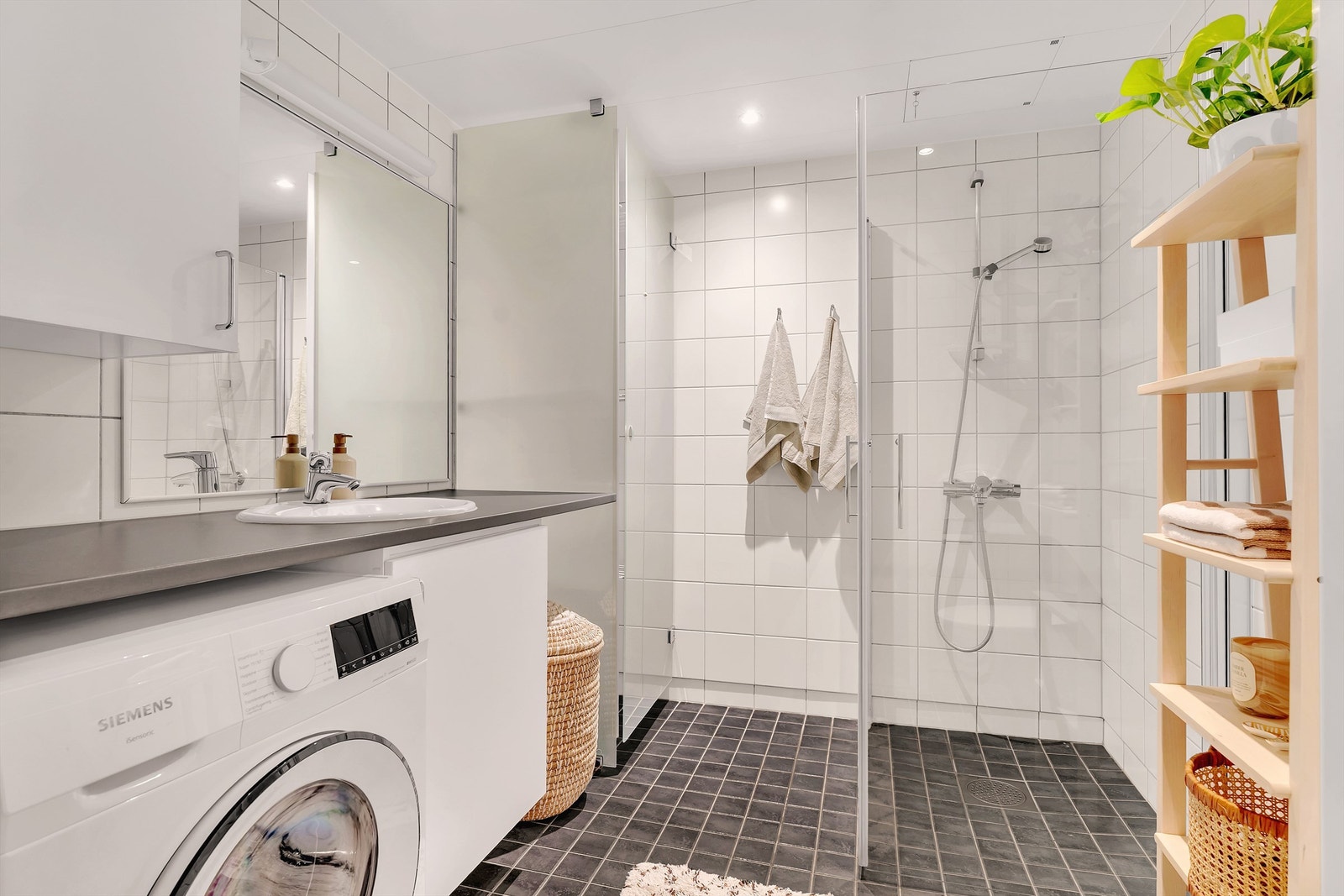 Innbydende og meget romslig bad med hvite fliser på vegg, gråmelerte fliser med varme i gulv og downlights i himling. Galleribilde