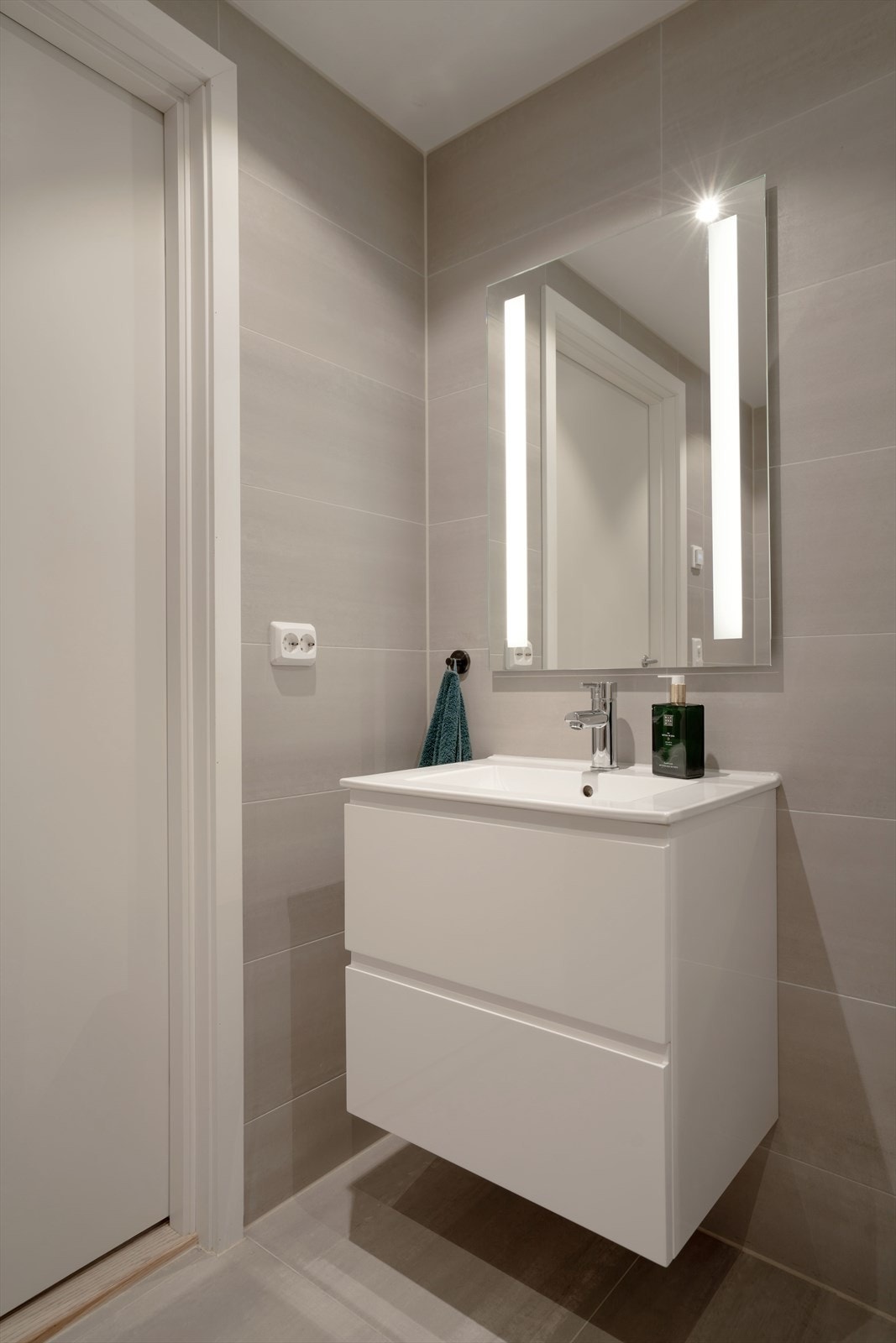 Badet har flislagte vegger i lyse, tidsriktige toner og flislagt gulv med elektriske varmekabler. Stilren baderomsinnredning med nedfelt servant og speil. Galleribilde