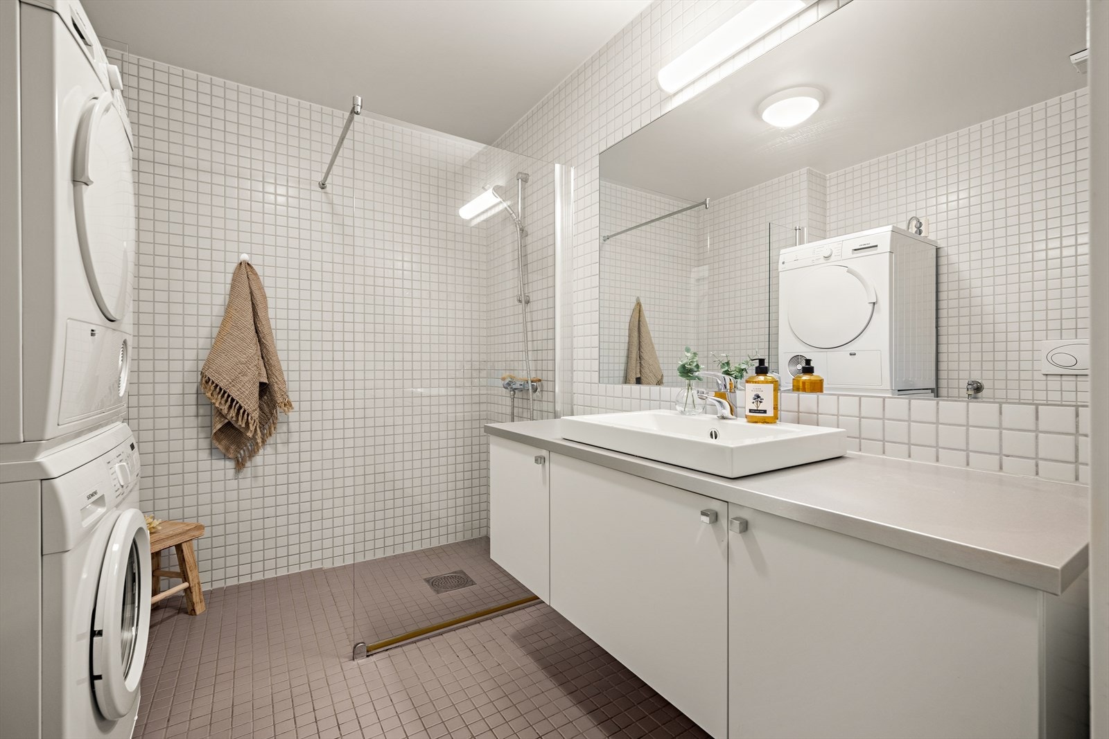 Romslig bad fra byggeår med flislagte overflater, vannbåren gulvvarme og innfelte downlights i himling. Det er opplegg for vaskemaskin. Galleribilde