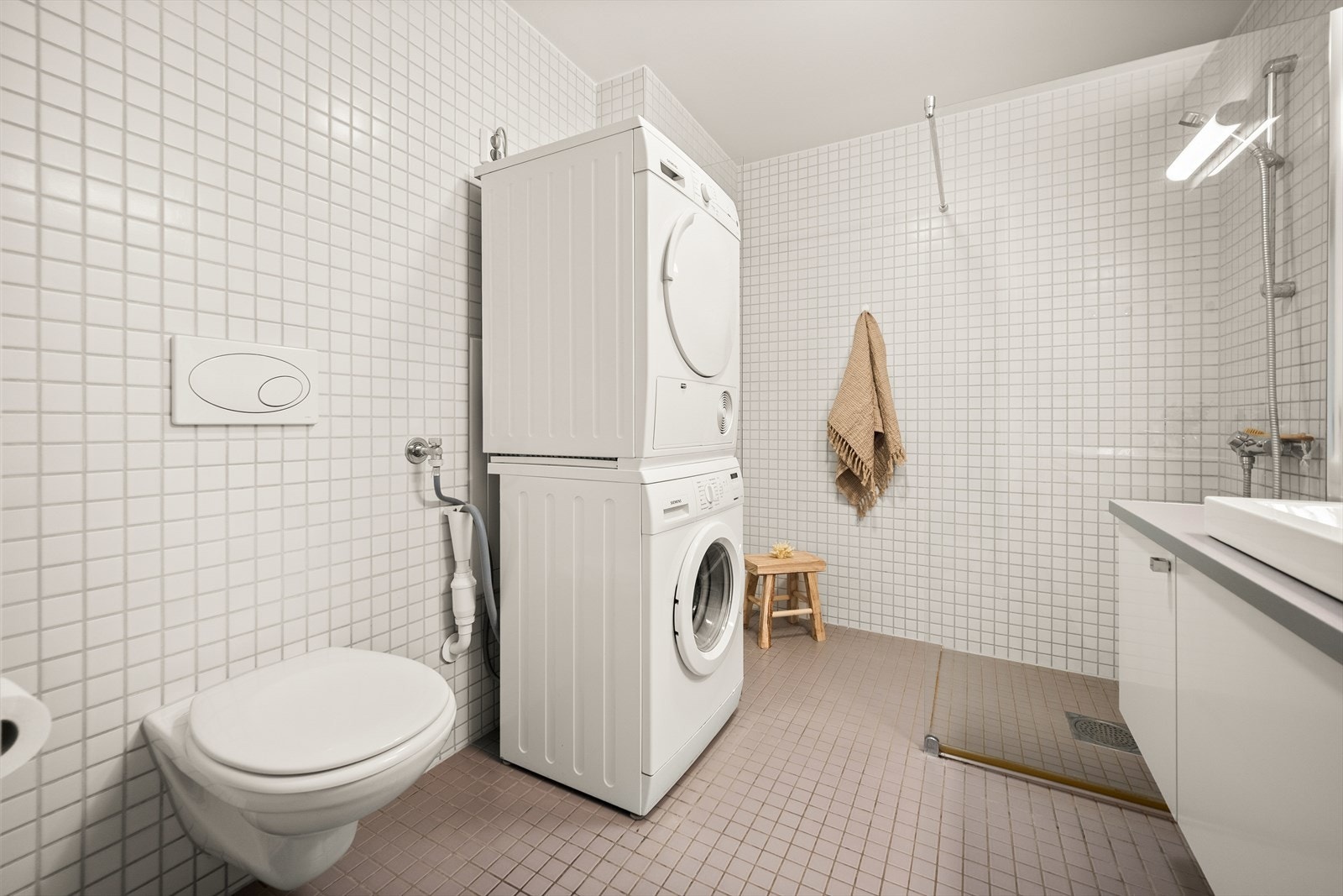 Badet er utstyrt med vegghengt toalett, dusjhjørne med glassvegger og en bred baderomsinnredning med nedfelt servant, skap og speil med belysning. Galleribilde