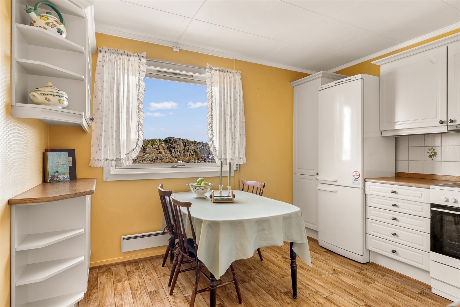 Kjøkkenet fremstår som praktisk og innbydende, med en tidløs innredning bestående av profilerte fronter som gir et klassisk og hyggelig uttrykk. Galleribilde