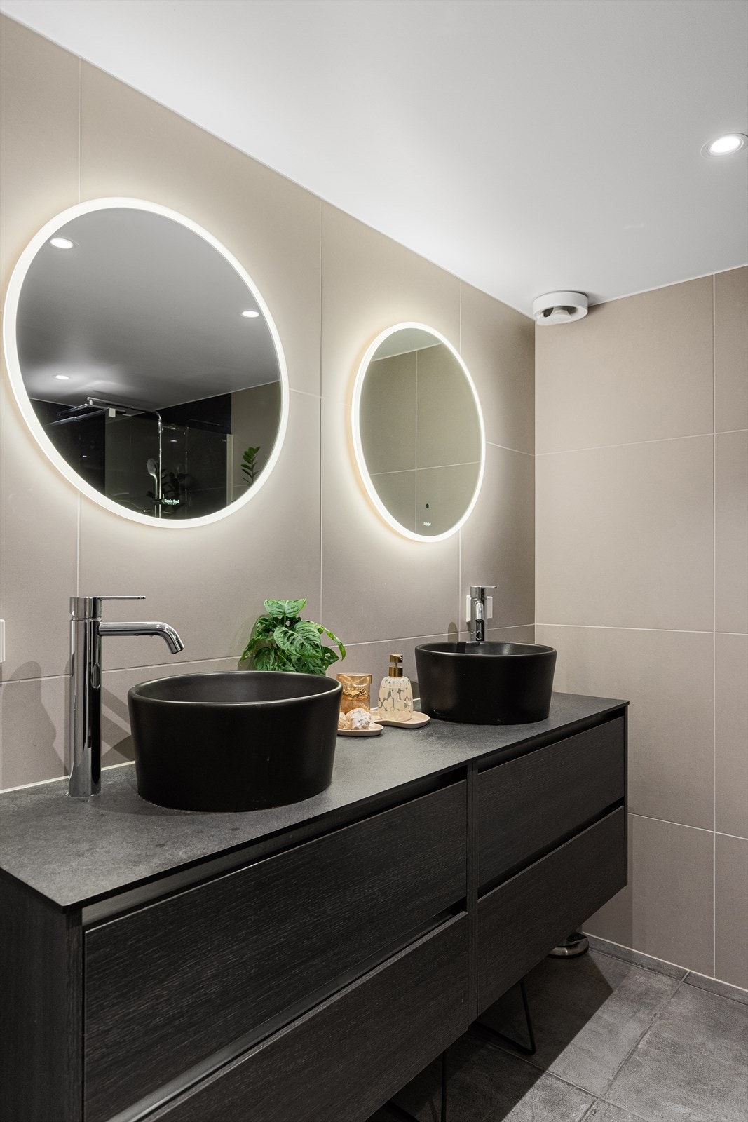 Badet er holdt i moderne farger med store fliser på gulv og vegg Galleribilde