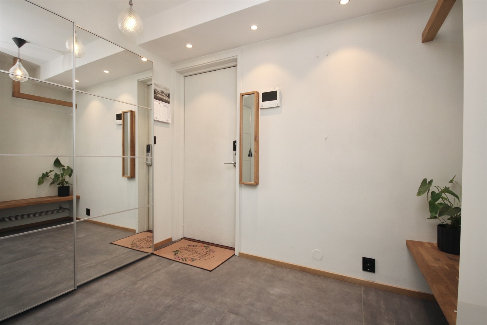 Flislagt entré med skyvedørsgarderobe og plassbygd benk/oppheng for yttertøy og sko. Galleribilde