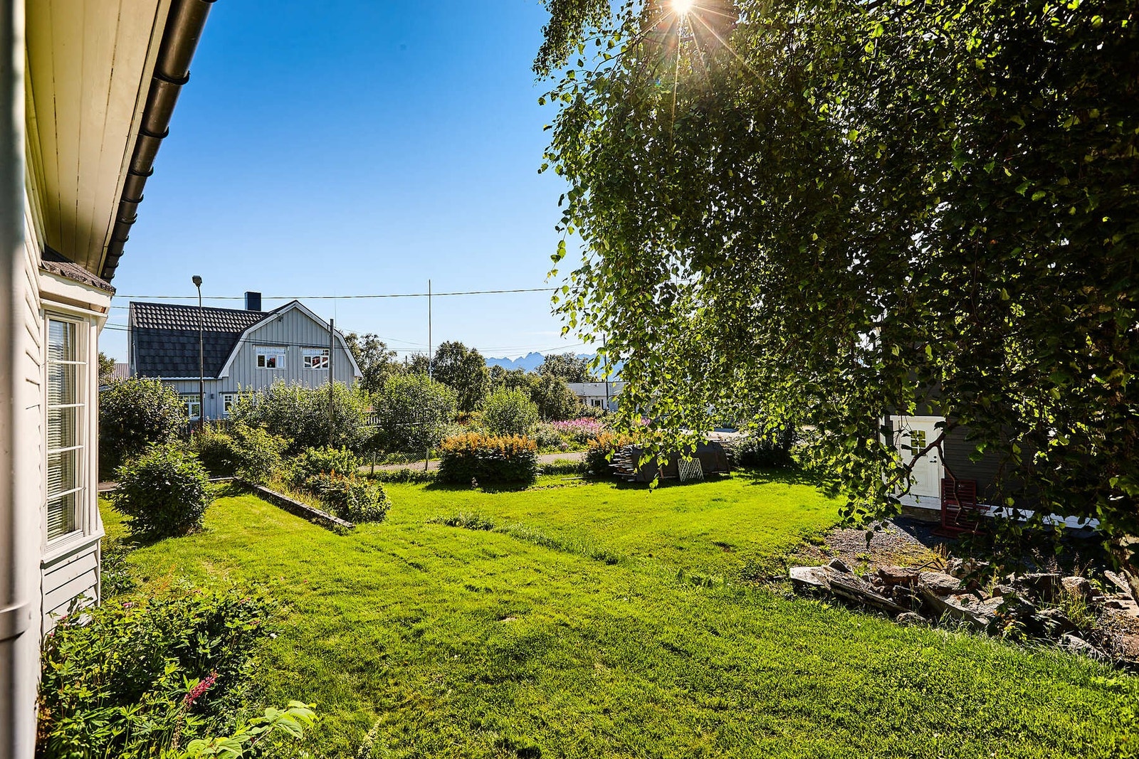 Tomten er pent opparbeidet med plen og diverse prydbusker. Galleribilde