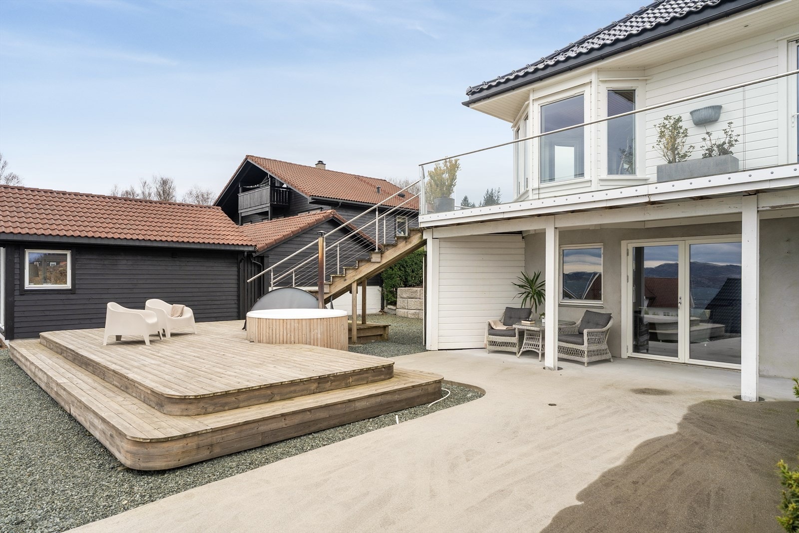 Fra terrassen er det trapp ned til bakkeplan hvor det også er terrasse, badestamp, en stor betongplatting og hage. Galleribilde