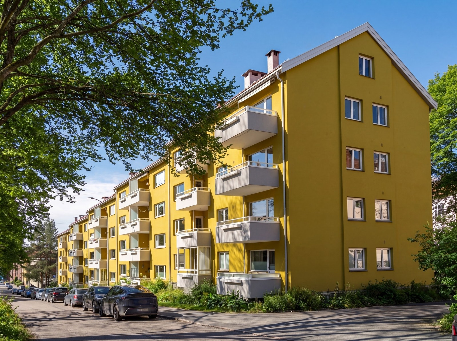 Beboerne i Vossegata borettslag skryter av et trivelig og imøtekommende bomiljø med hyggelige naboer. Borettslaget består av 40 andelsleiligheter i ulike størrelser fra 60-tallet. (Bildet er KI-redigert for å illustrere sol- og sommerforhold. Avvik kan fo Galleribilde