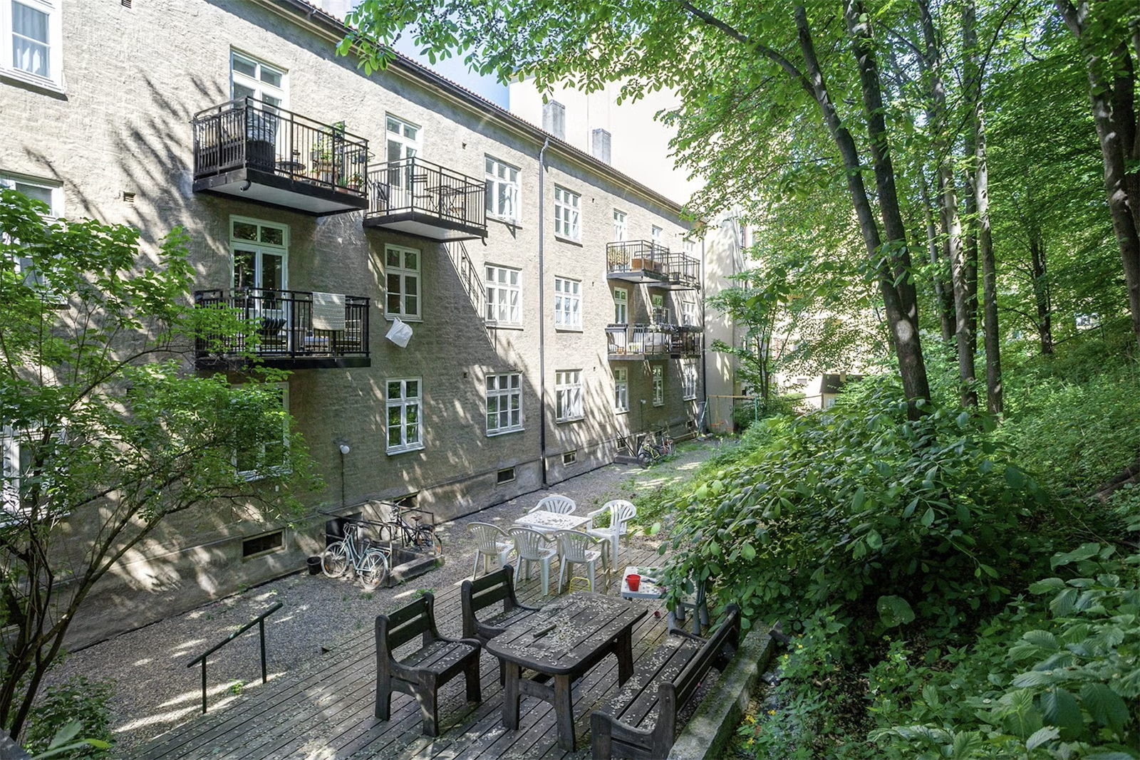 Frodig bakgård med terrasse og sittegrupper. Galleribilde