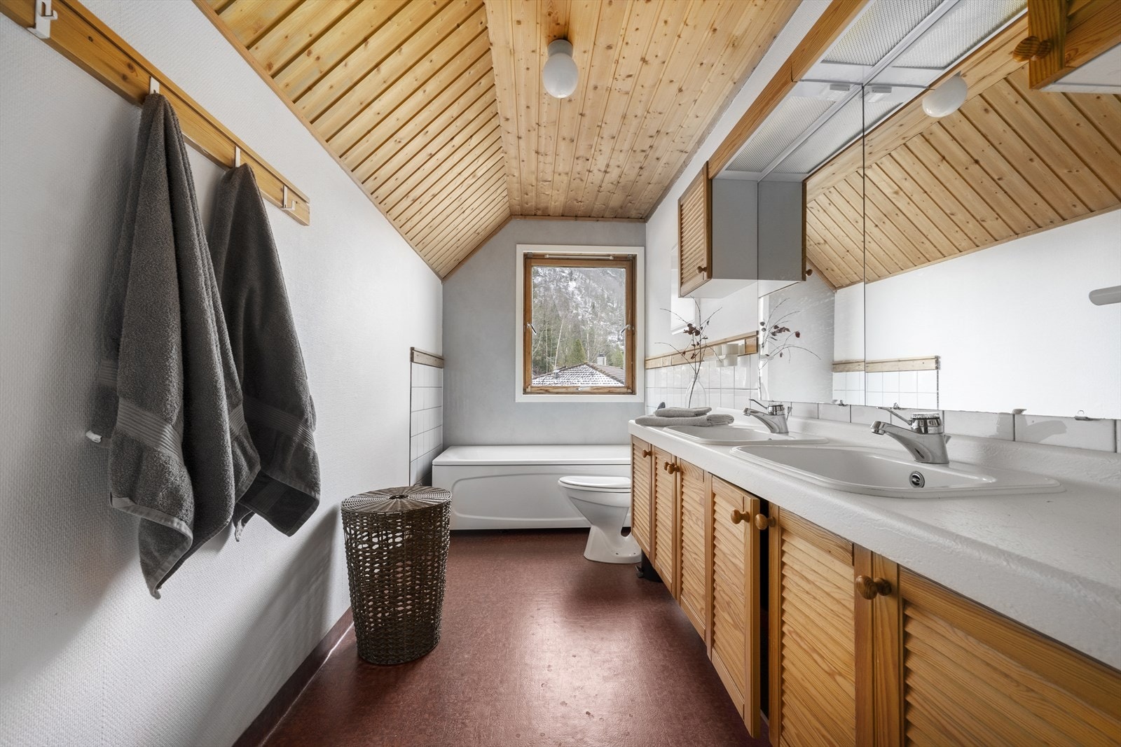 Romleg bad på loftet med fliser på delar av veggene og opplegg for vaskemaskin. Galleribilde