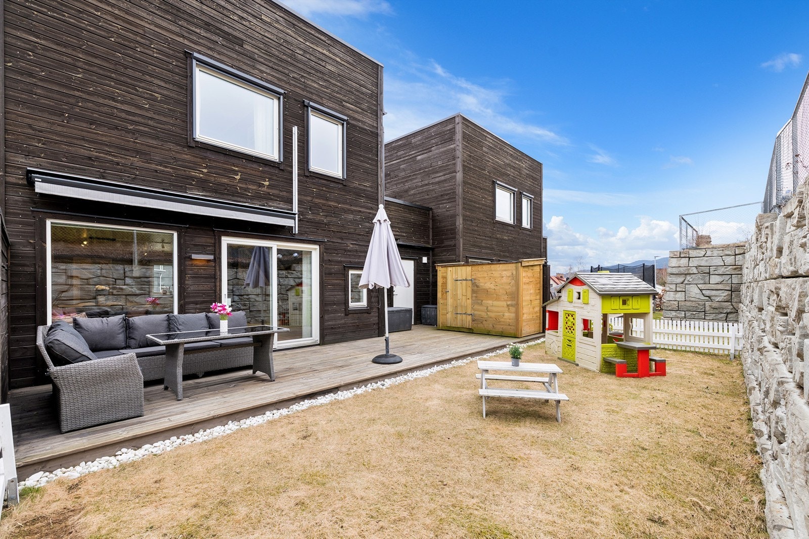 Fra stuesiden er det utgang til en hyggelig markterrasse med fin terrassemarkise og praktisk lagringsbod for utemøbler mm. Fint plenareale som innbyr til lek for viltre småtasser. Foto: Digit Media AS v/Jørgen Sørebø Galleribilde