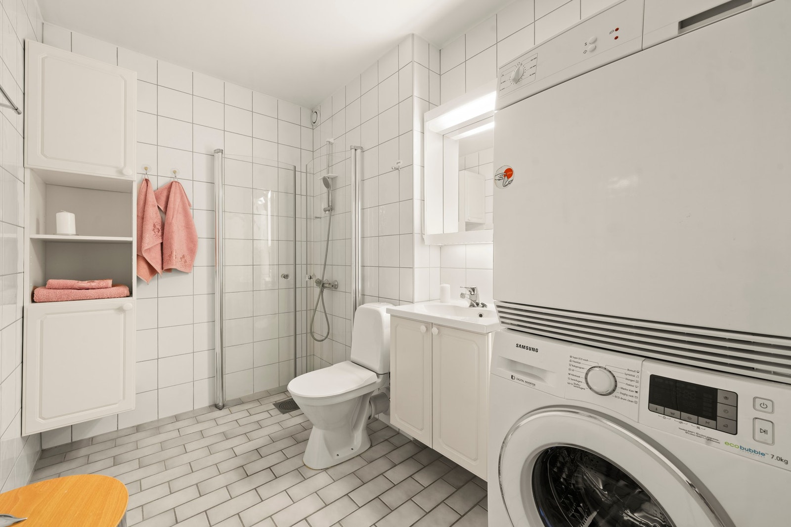 Bad i første etasje med baderomsinnredning bestående av benkeskap med glatte fronter, speil med belysning over og flislagte overflater. Galleribilde