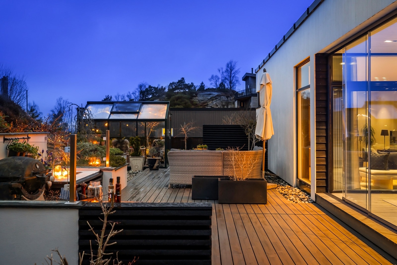 Nydelig uteområde med treterrasse omkranset av flott beplantning. Utekjøkken og flott høykvalitets drivhus i glass og aluminium. Galleribilde