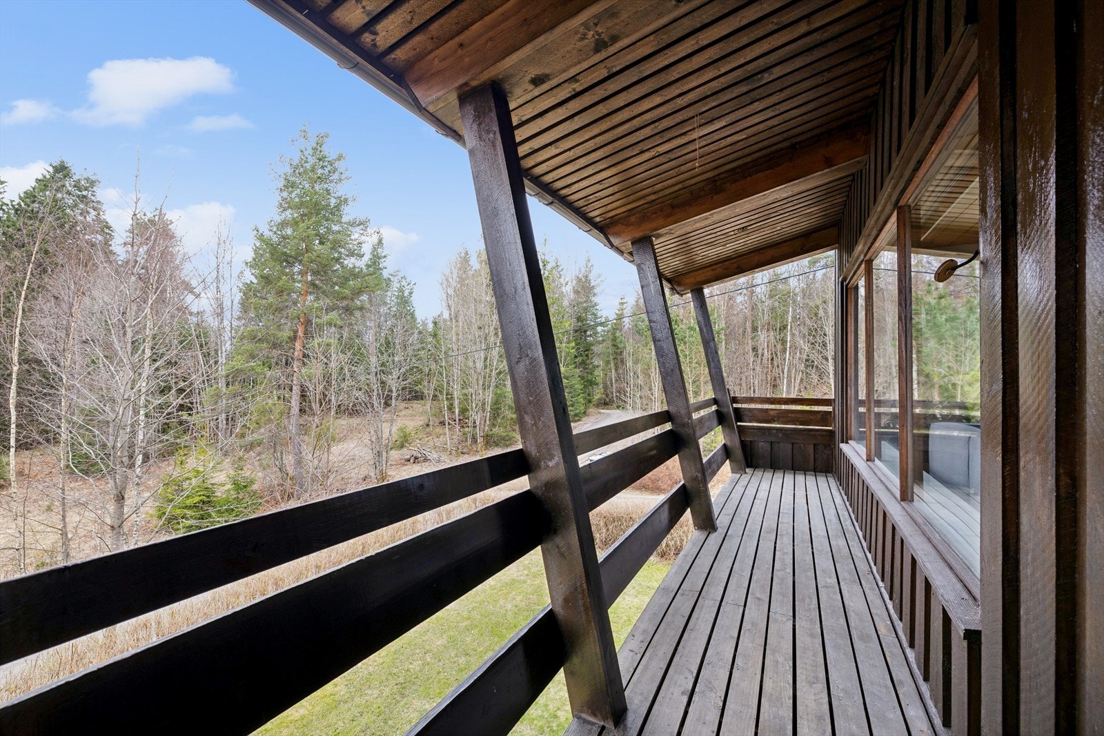 Balkongen har rekkverk i tre og terrassebord som gulv. Galleribilde