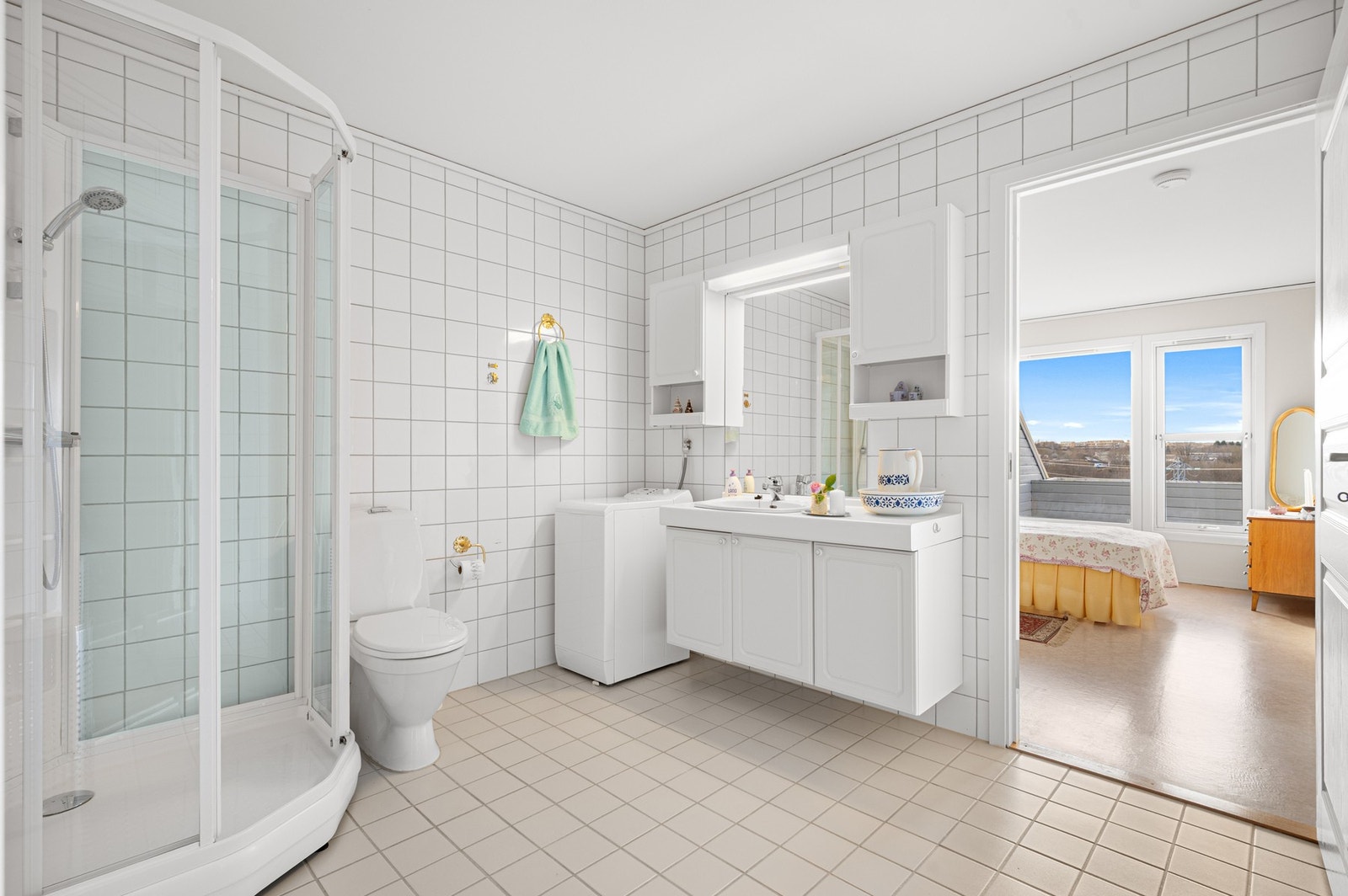 Badet er utstyrt med gulvmontert toalett, dusjhjørne, servant på underskap, og speil. Det er også opplegg til vaskemaskin. Galleribilde