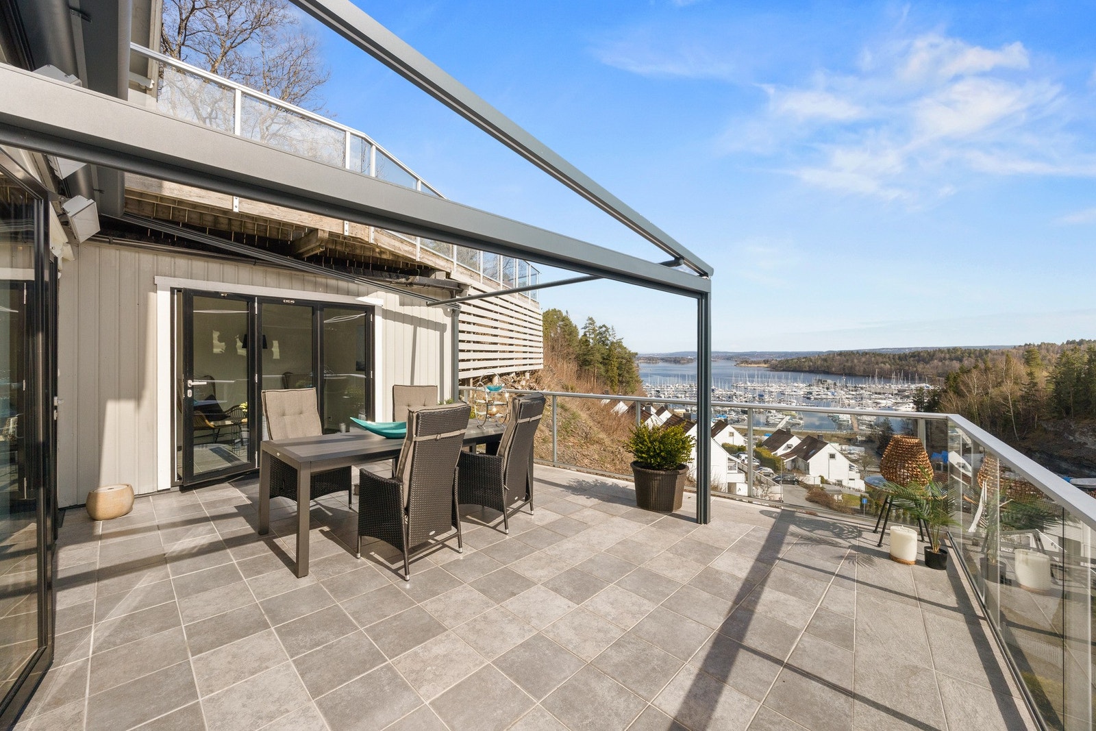 Stor terrasse med utsikt over marina og fjord. Glassrekkverk gir åpen følelse. Galleribilde