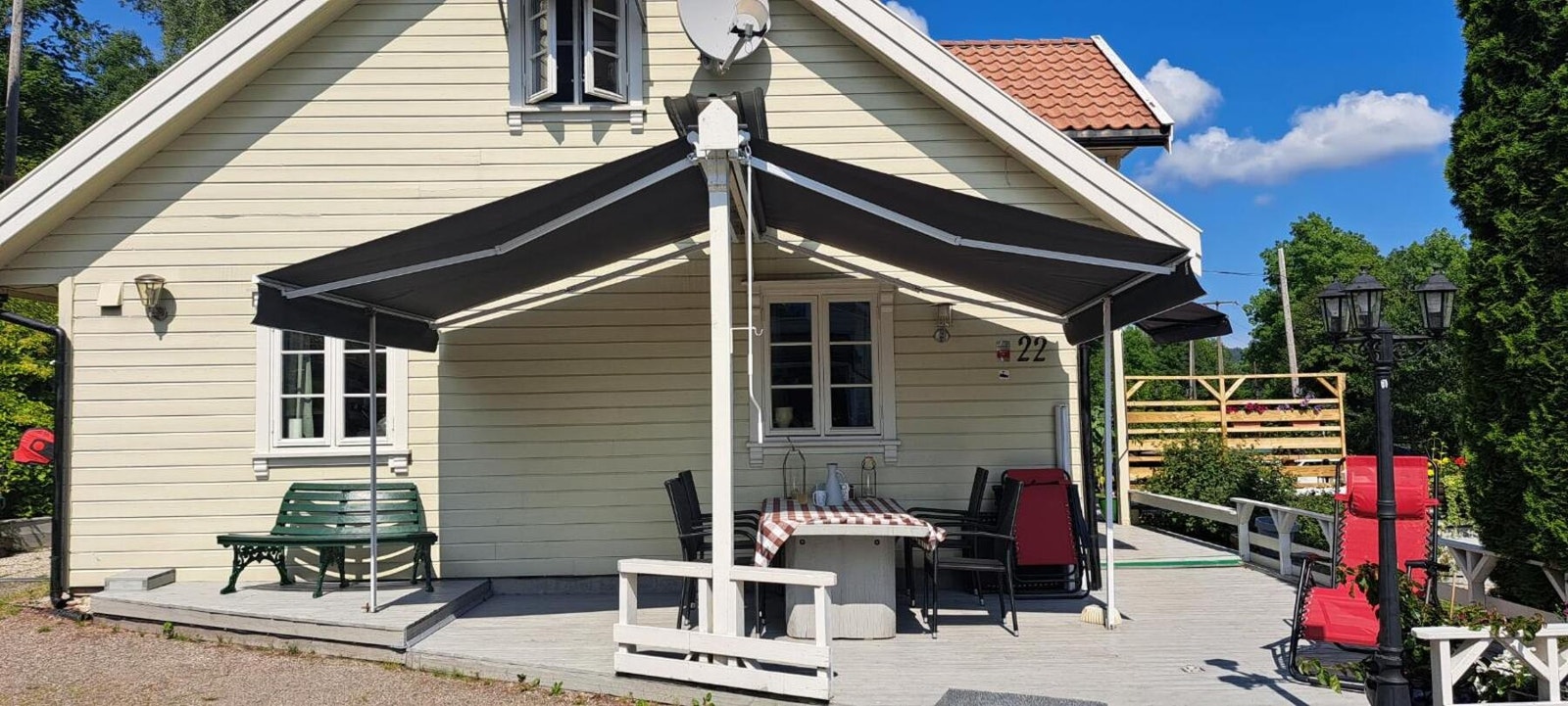 Selgers bilde av en fin solrik uteplass utenfor huset med 2 nyere markiser Galleribilde