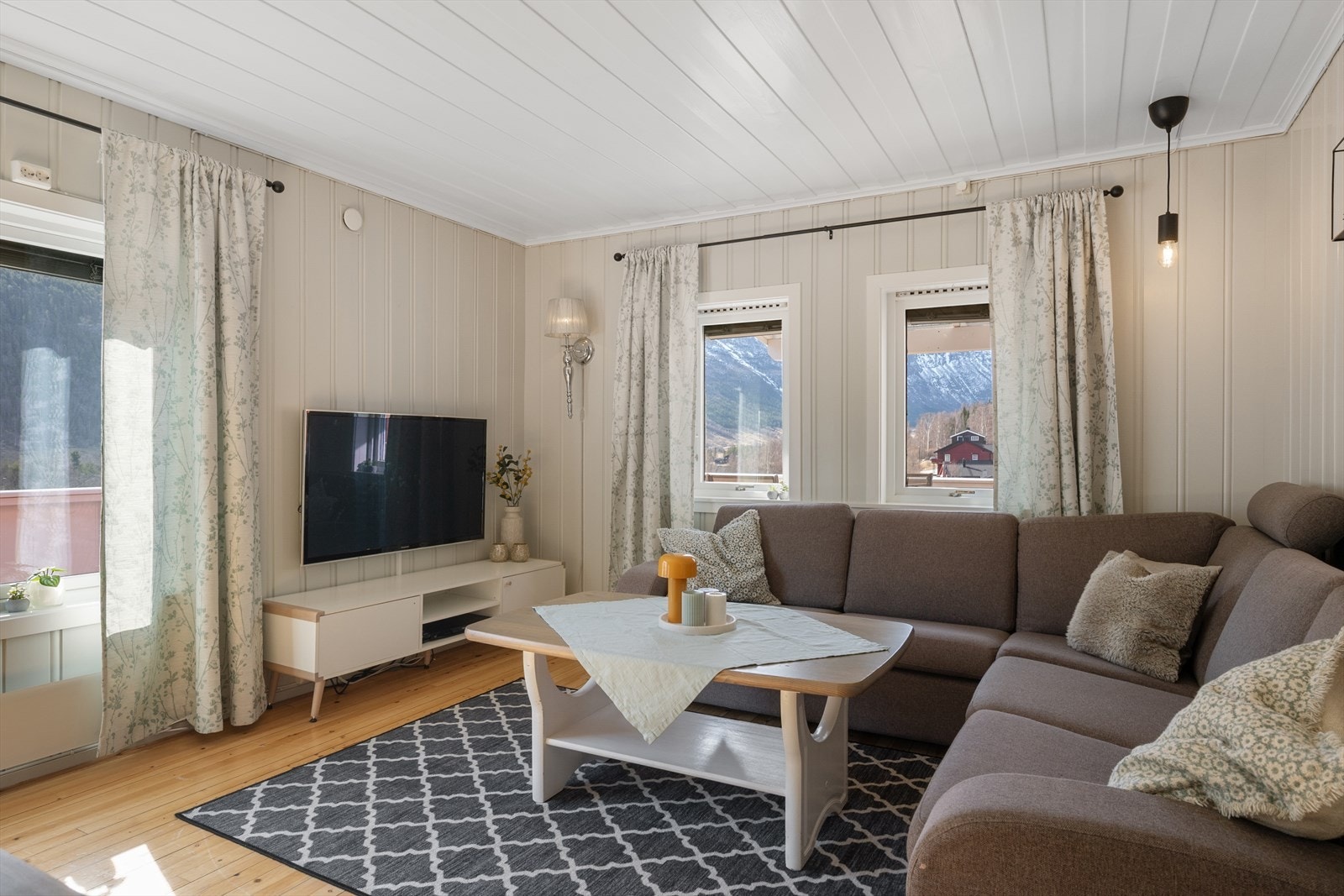 Det er gjennomgående overflater med tregulv og malte panelvegger som skaper en helhetlig stil i oppholdsrommene. Galleribilde