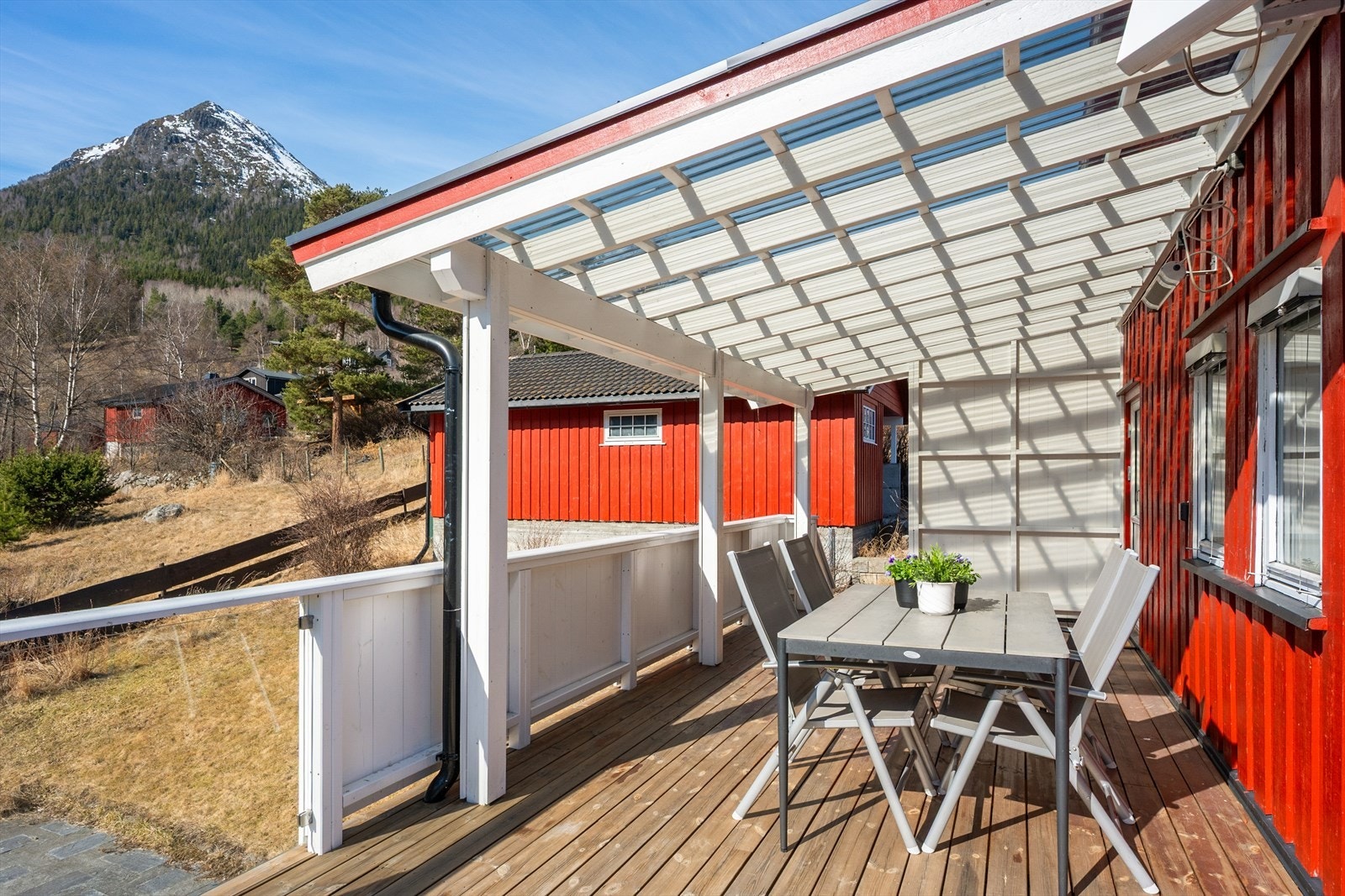 Verandaen er bygget med impregnerte materialer og har rekkverk med stående bord og glass. Galleribilde