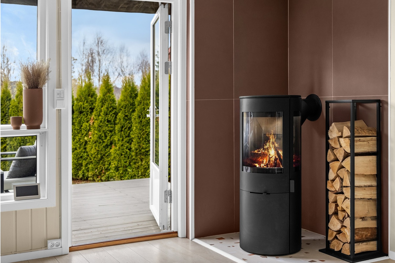 En stilren peisovn fra Nordpeis (2025) tilfører både ekstra hygge og behagelig varme på kjølige dager. Rundt peisen er det lagt eksklusive fliser fra Italia. Galleribilde