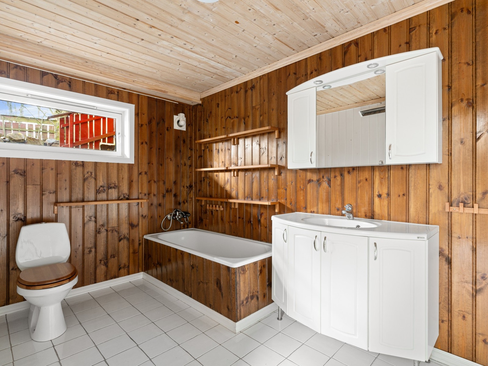 Badet i kjeller har fliser på gulv og er utstyrt med servantinnredning, badekar og toalett. Galleribilde