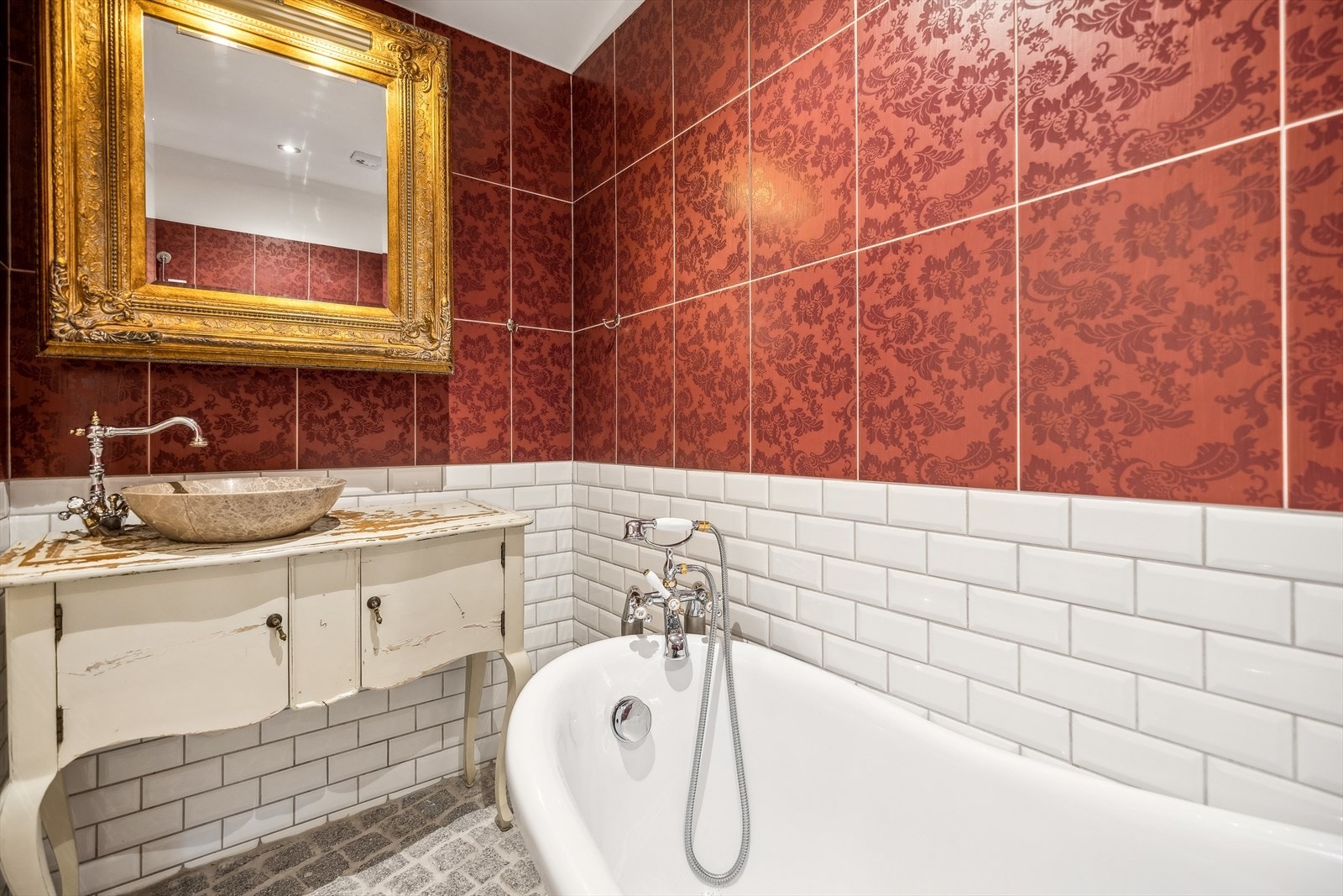 Badet har fliser på vegger og brostein på gulvet Galleribilde