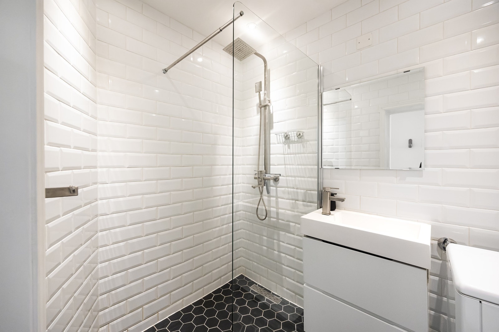 Videre er det vegghengt toalett og dusjnisje med glassvegg som er tilkoblet både hånd- og regndusj. Det er opplegg for vaskemaskin på badet. Galleribilde