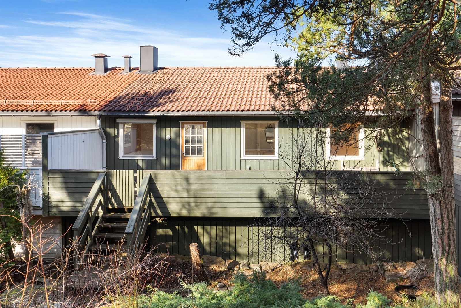 Baksiden av boligen vender mot et grøntareal. Her er det trapp ned til hagen fra den ene av boligens to verandaer. Galleribilde