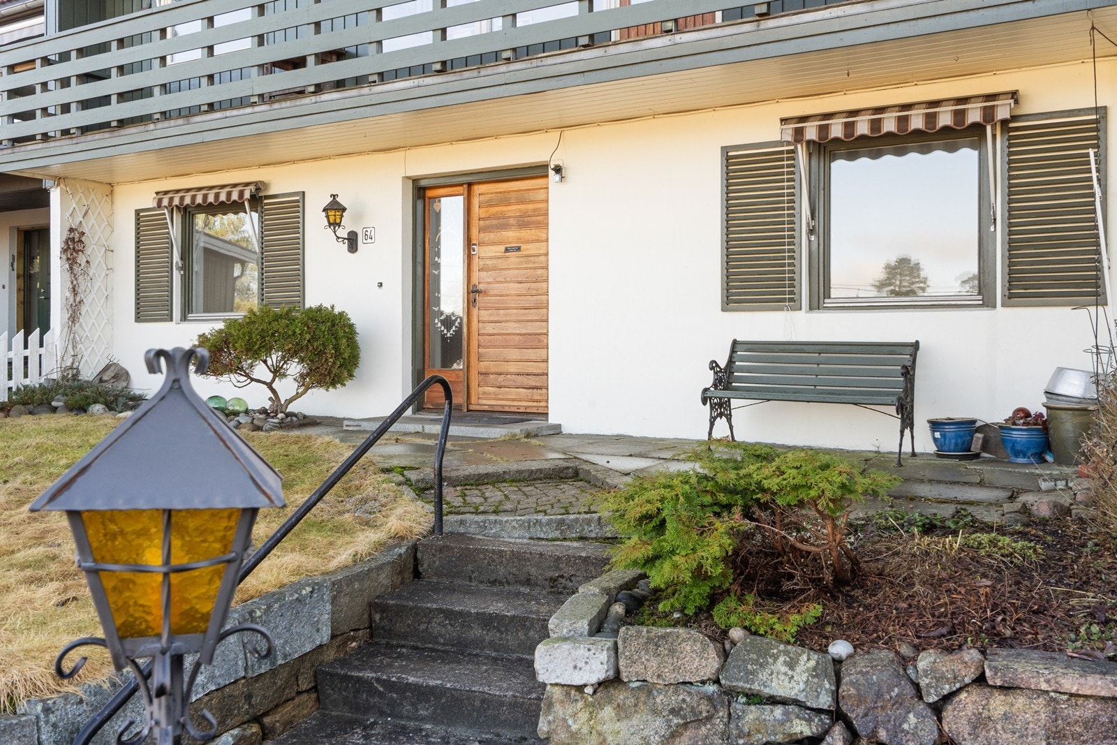 Adkomst til boligens hovedinngang via en betongtrapp. Uteområdet er opparbeidet med gressplen, skiferplatting og forstøtningsmurer i naturstein. Galleribilde
