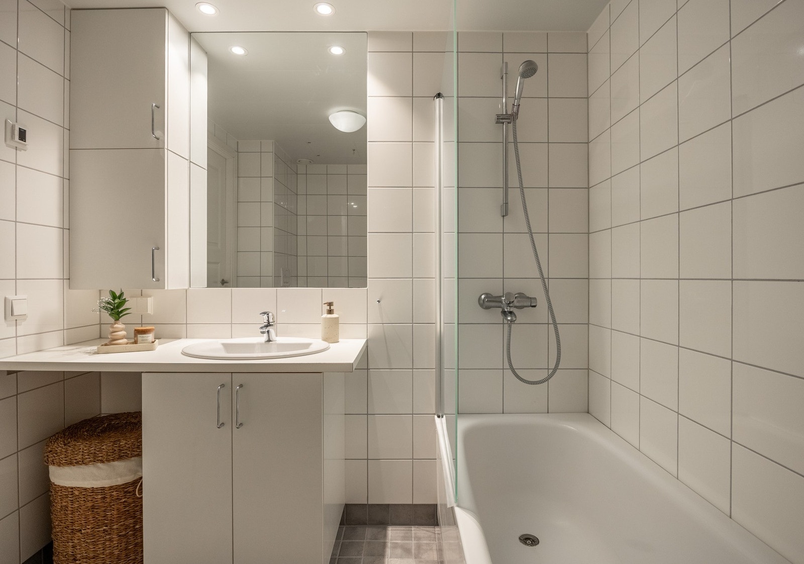 Badet er innredet med vegghengt servantinnredning, ovenpåliggende servant med armatur, speil med overlys, skap over servant, badekar med vegghengt badekararmatur, samt vegghengt toalett. Galleribilde