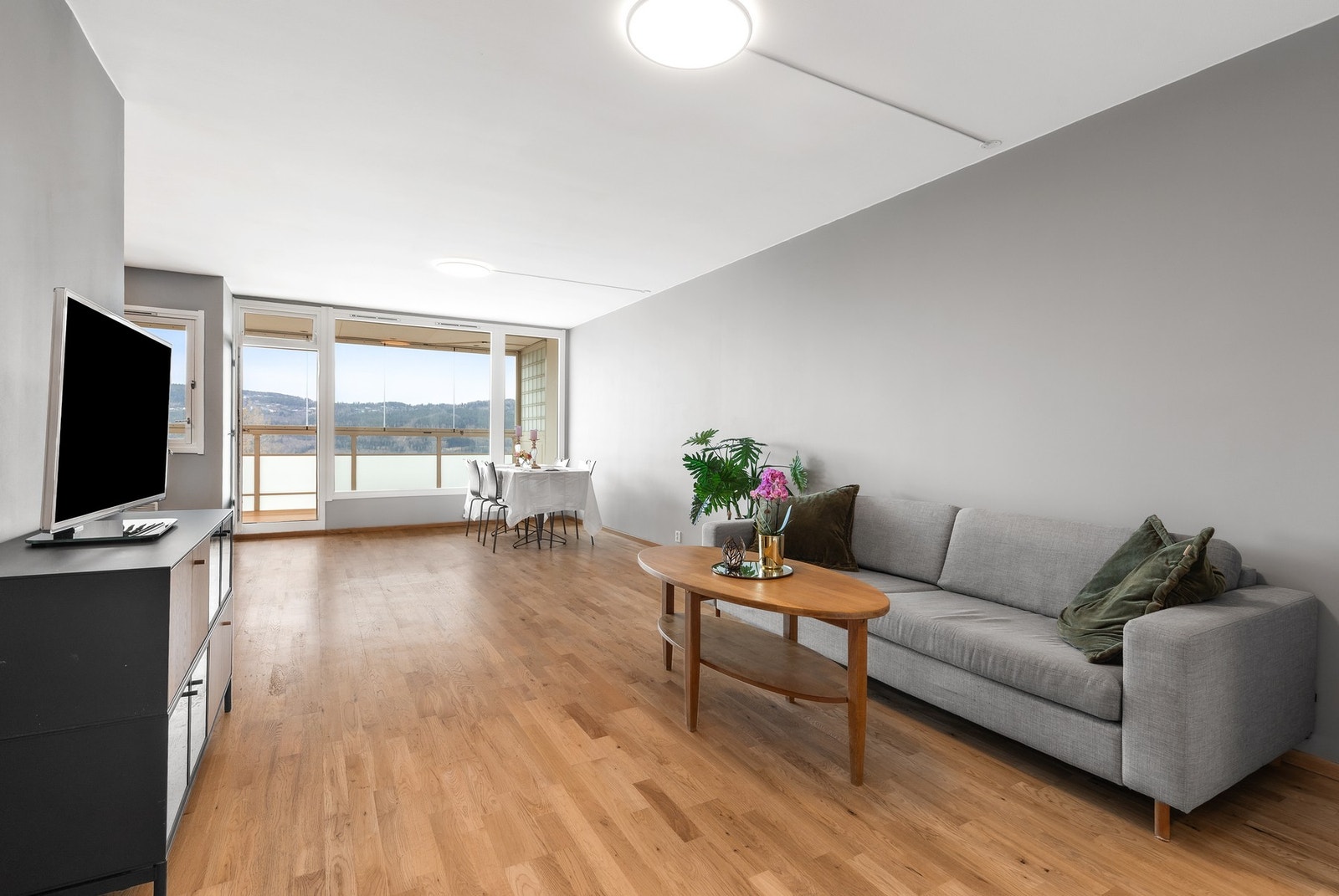 Lys og innbydende stue med 3-stavs parkett på gulv og malte, slette flater på vegger og i himling Galleribilde