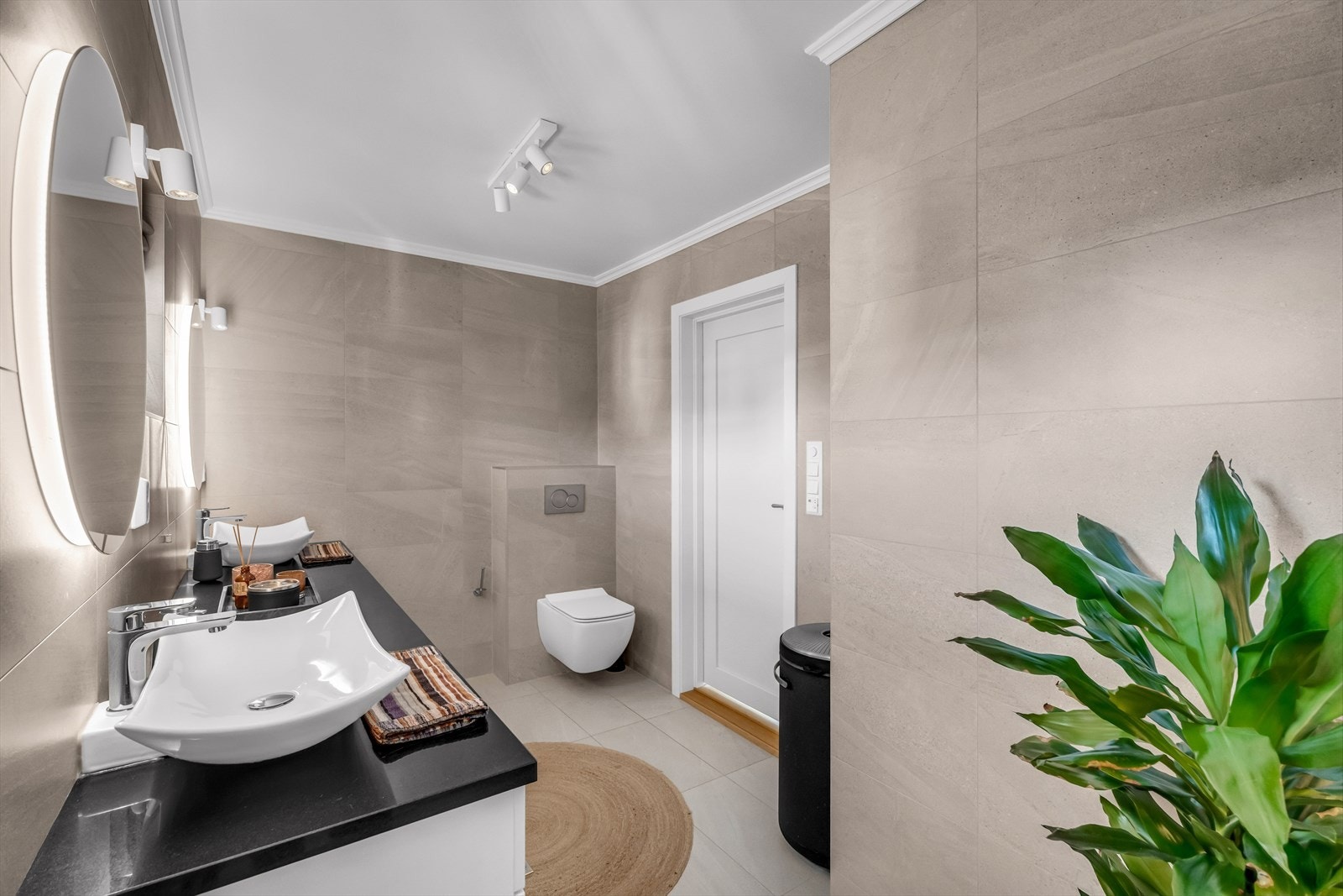 Badet er utstyrt med vegghengt toalett og store, moderne fliser. Galleribilde