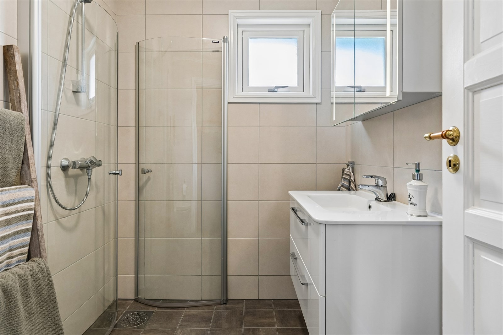 Badet oppe er helfliset i grånyanser og har innredning med heldekkende servant over skuffeseksjon og speilskap med integrert belysning i overkant. Galleribilde