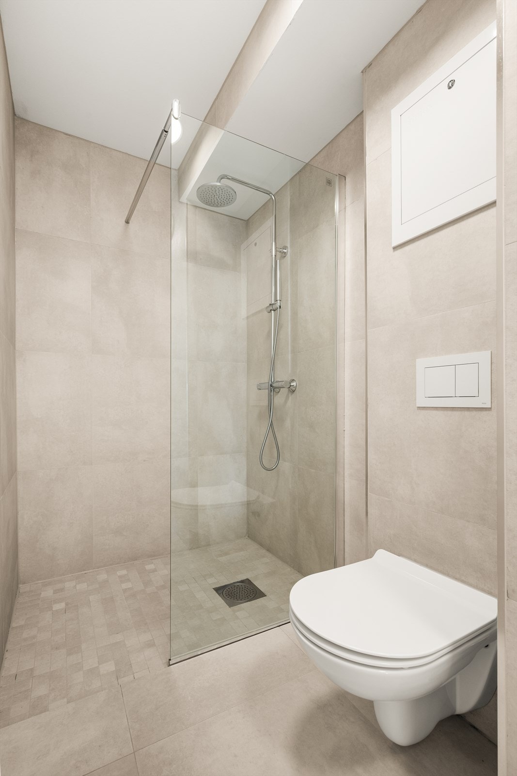 Dusjhjørne med moderne flisvalg. Badet har mekanisk avtrekk. Galleribilde