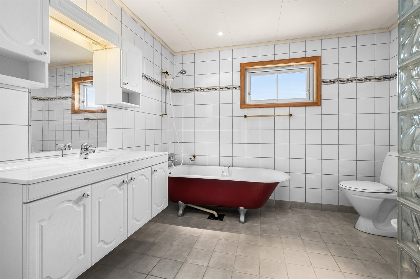 Romslig bad med flislagte overflater, godt med skapplass og en klassisk innredning med badekar som gir rommet særpreg. Galleribilde
