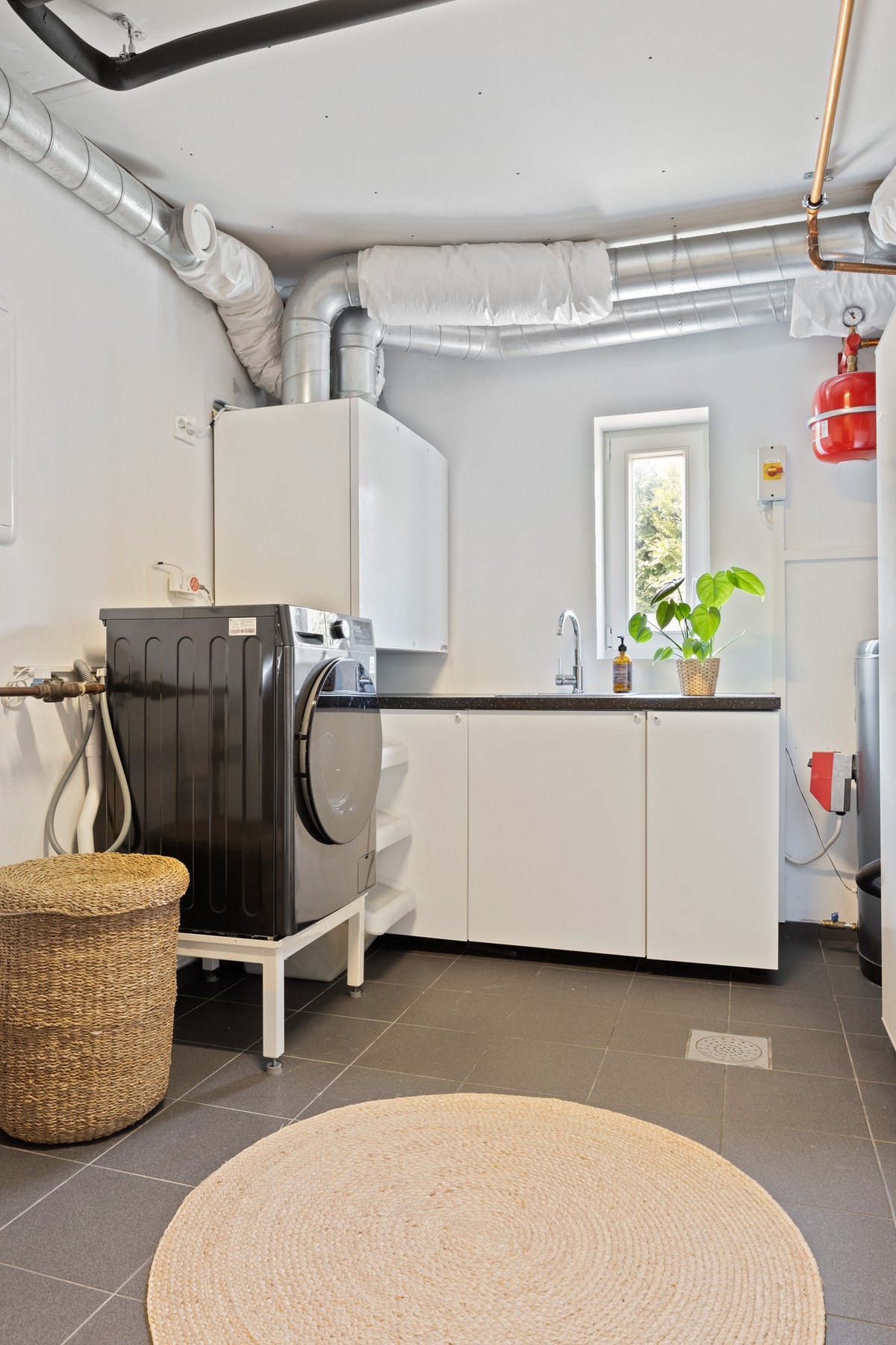 Vaskerom med praktisk innredning, inkludert vaskemaskin, skapplass og arbeidsbenk. Galleribilde