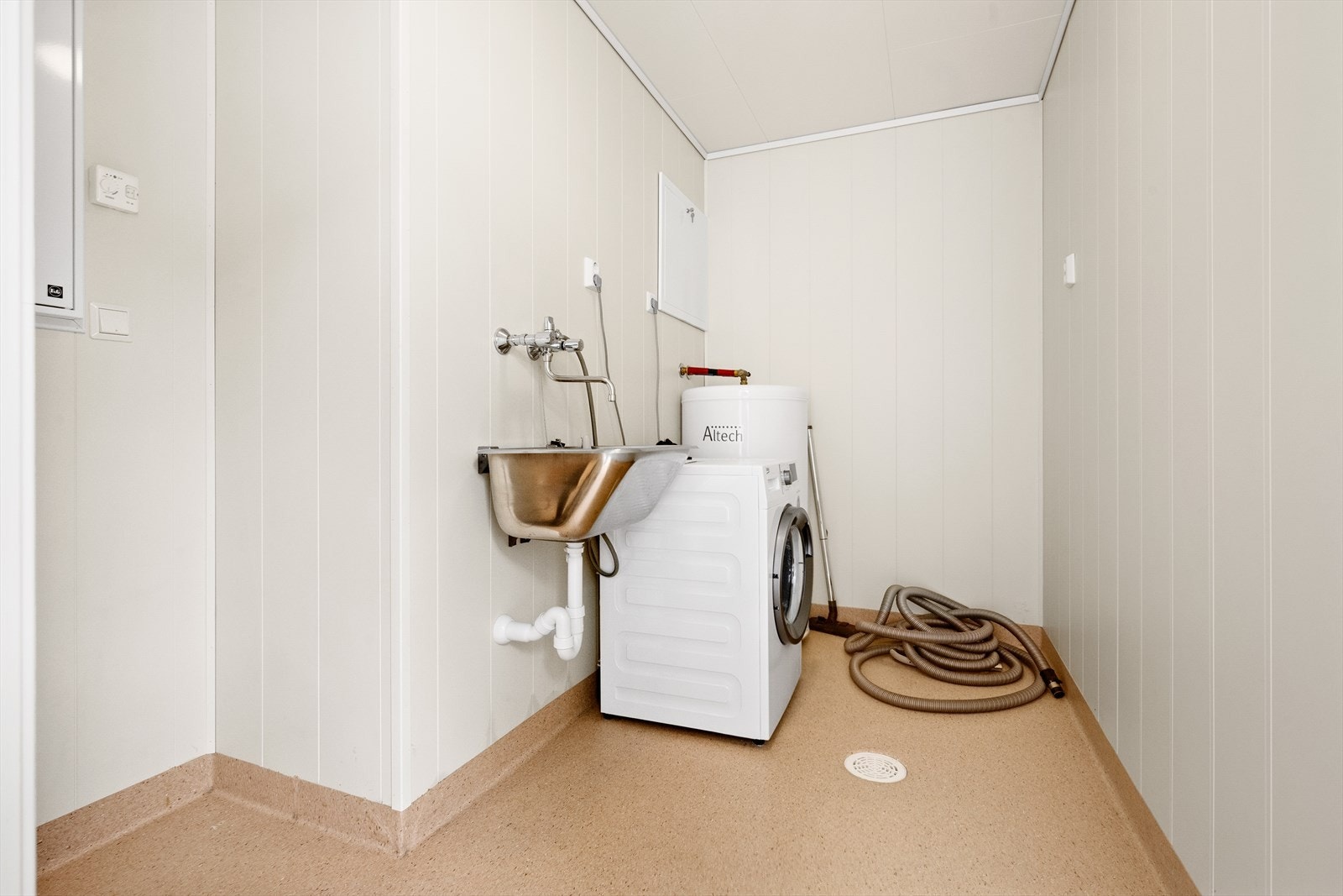 Separat vaskerom med opplegg til vaskemaskin og skyllekar i stål. Galleribilde